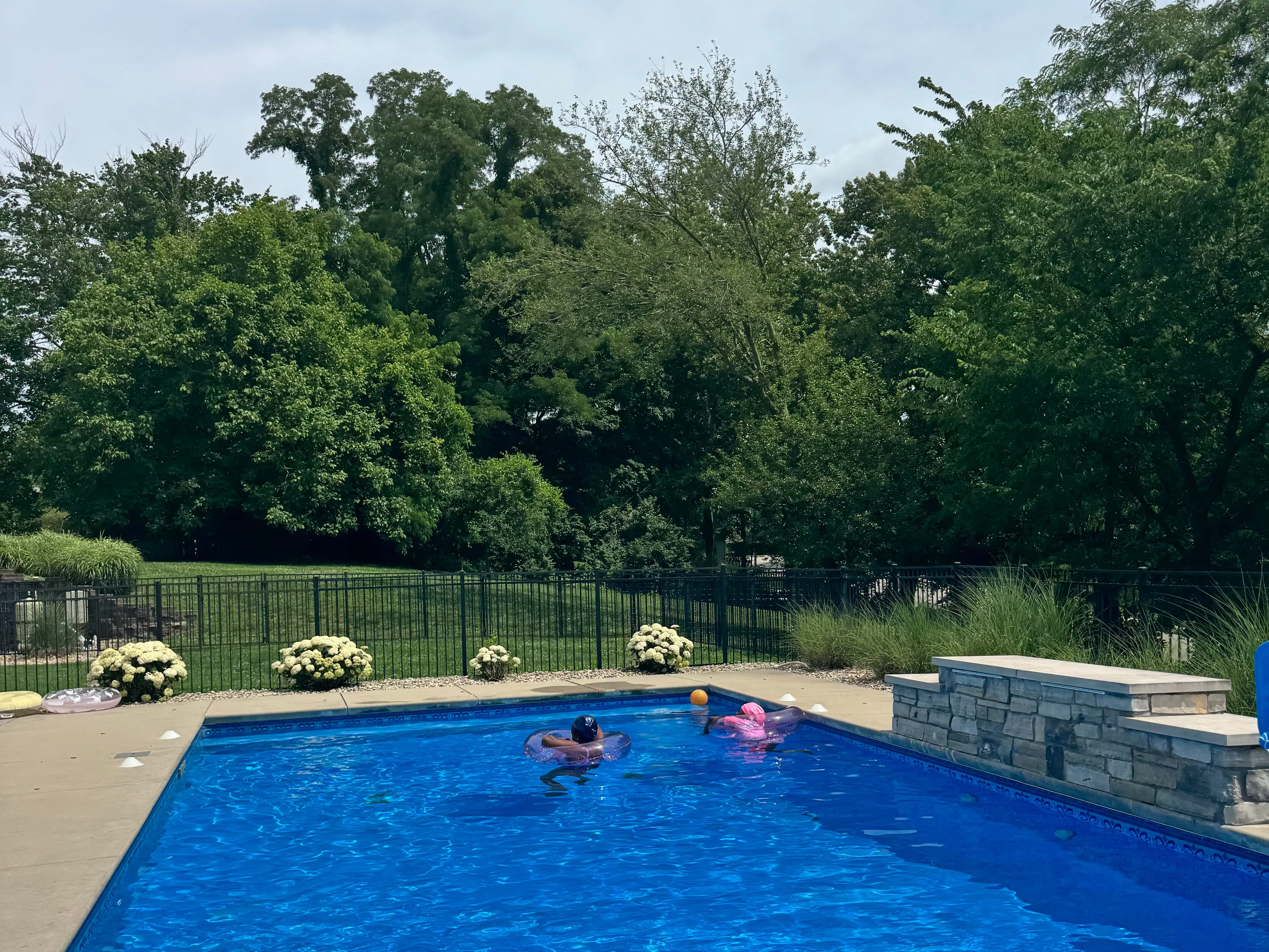 Two children play in a backyard pool.