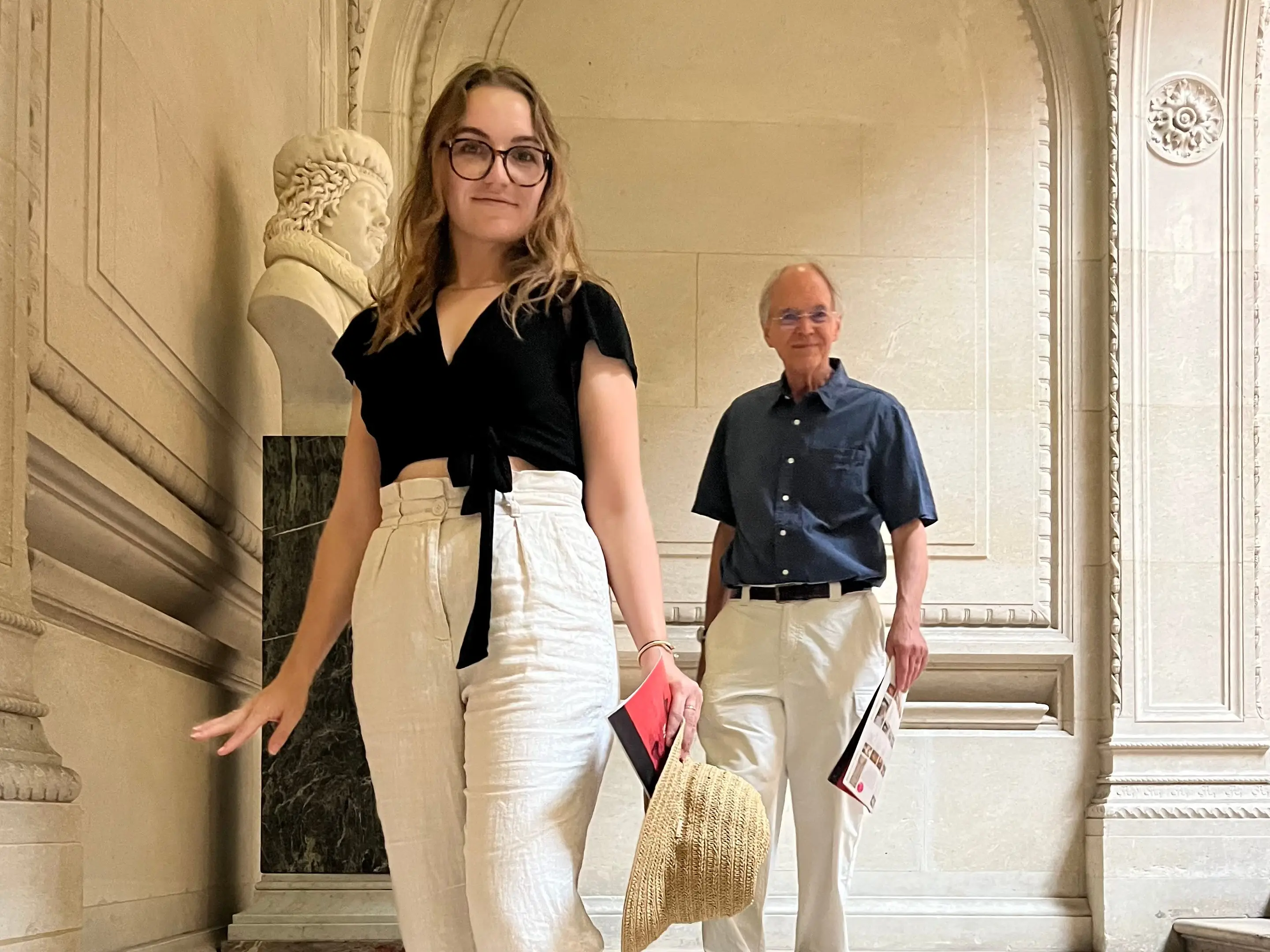 The writer and her father pose for a photo near an ornate bust in a museum in Paris.