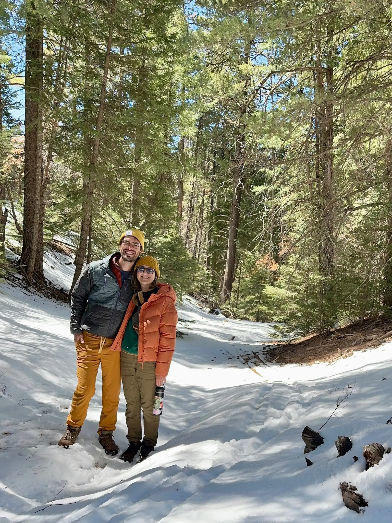 Sarah Silbiger and Jason Bernert stand on a snowy hiking trail in Cloudcroft, New Mexico.
