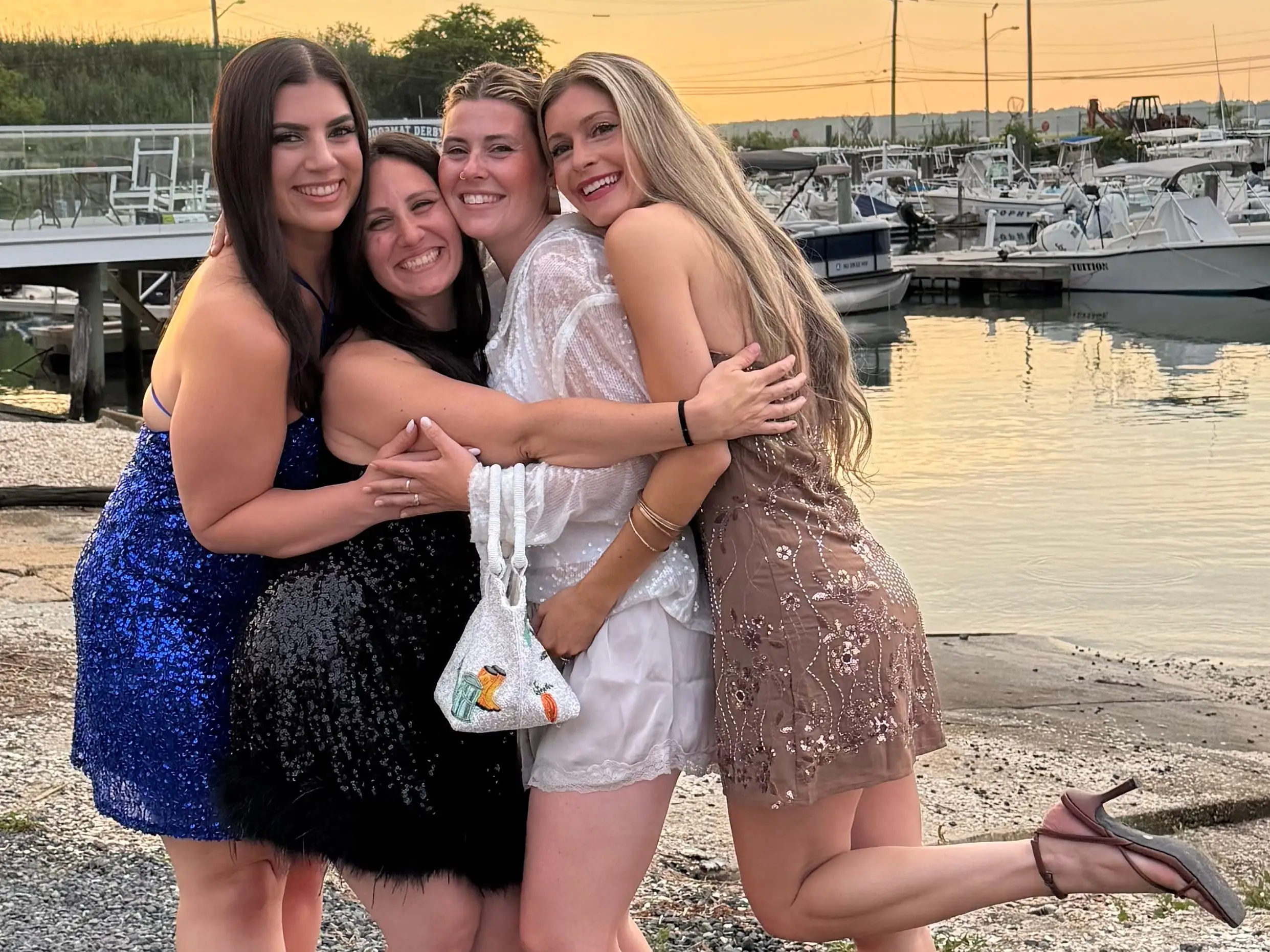 Four girls hugging on beach by water