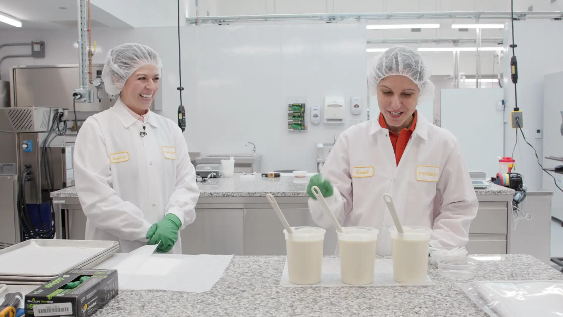 Business Insider senior producer Havovi Cooper (right) dressed in a clean white suit and hair net inside of a Ferrero testing facility.