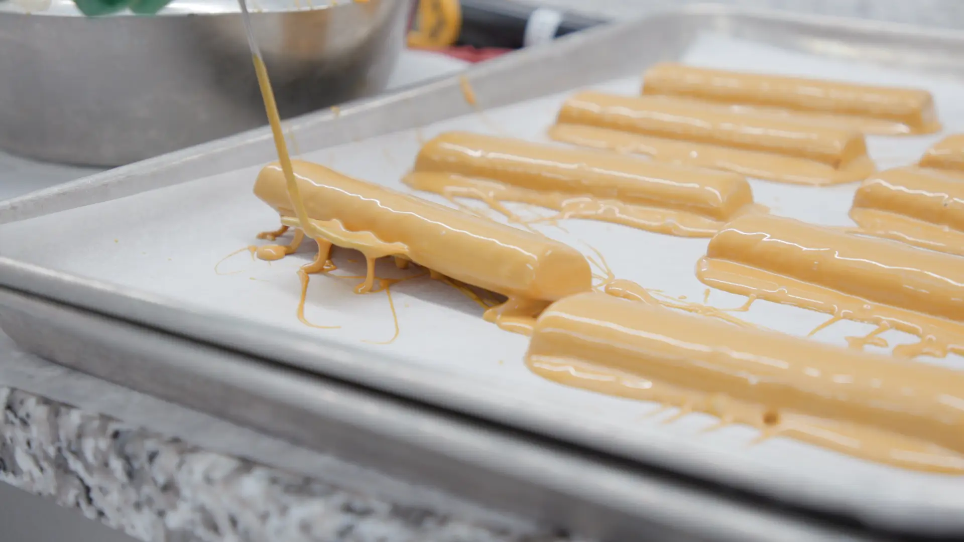 Bars of Butterfinger chocolate bars coated in an orange glossy liquid at Ferrero's testing facility in Chicago.