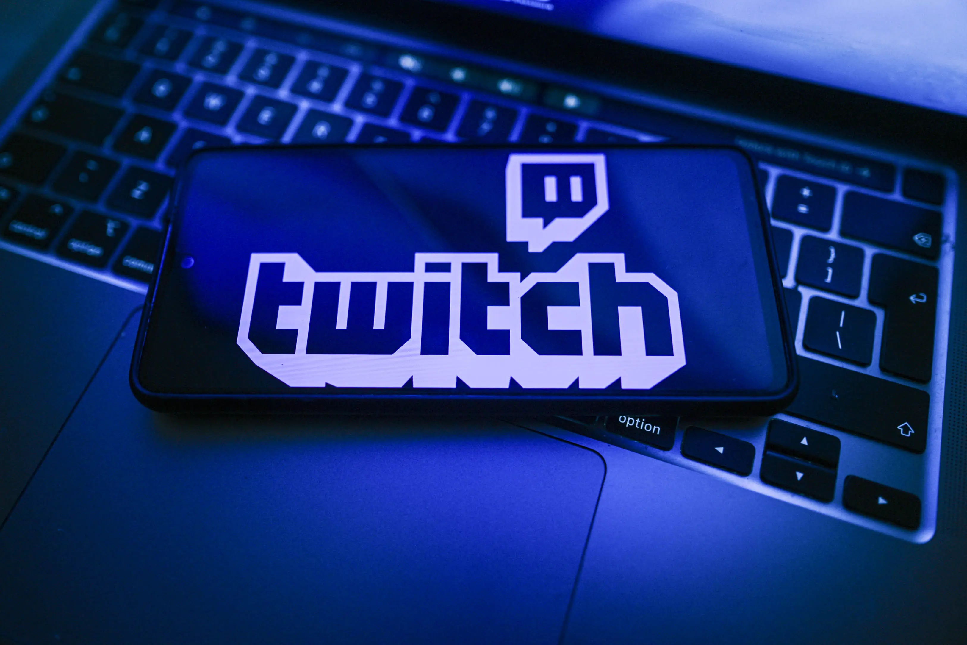 In this photo illustration, a Twitch logo is seen displayed on a smartphone on the top of a laptop.