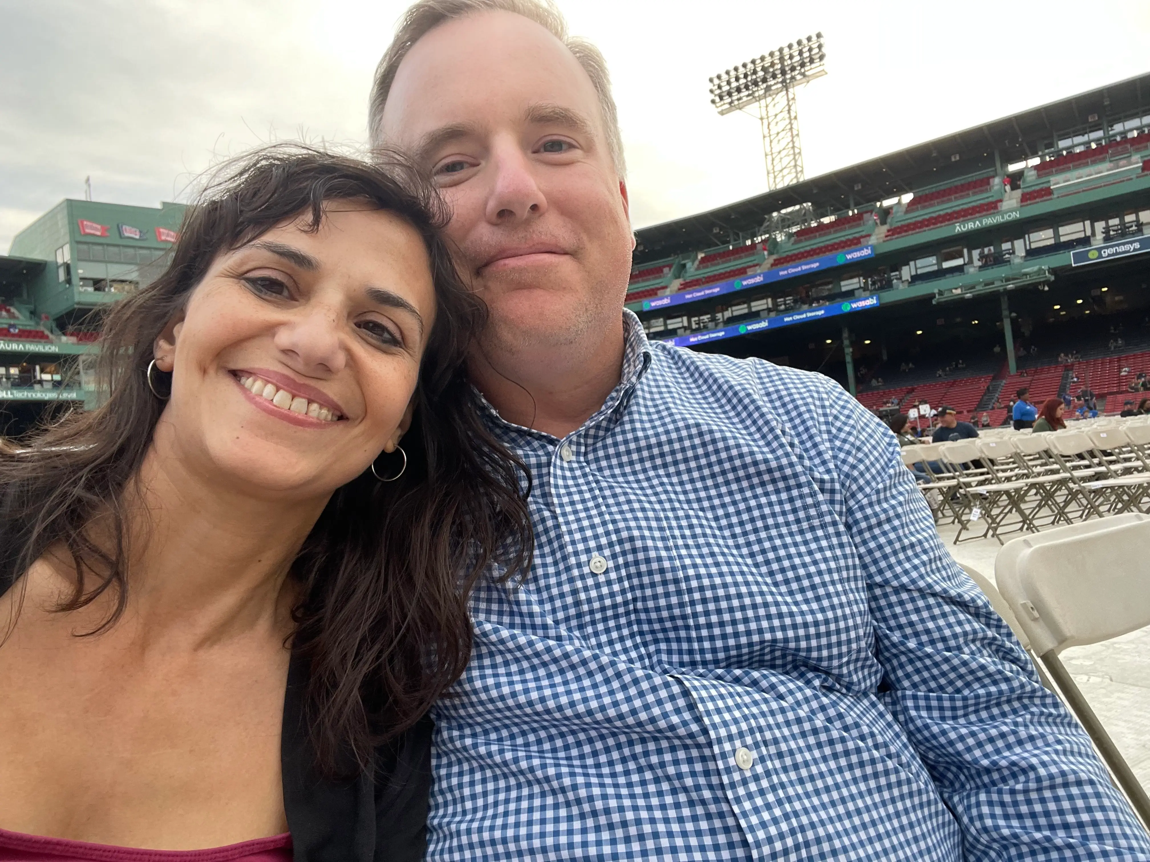 The author sits with her husband in seats on the floor of a stadium before a concert.