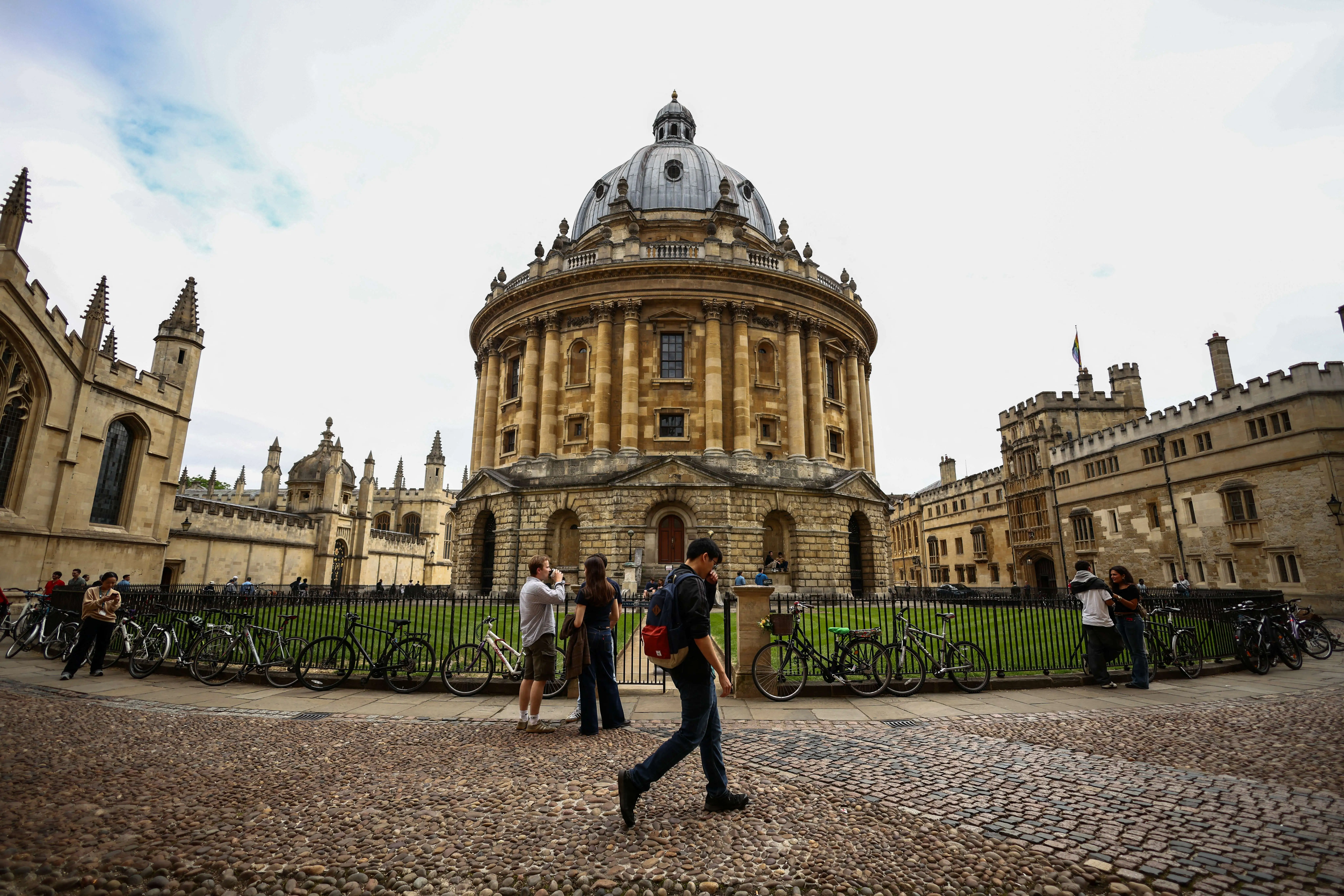People walking past the Radcliffe Camera building at Oxford University in Oxford, central England.