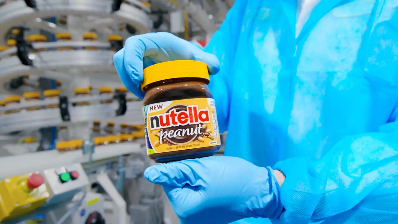 A person holding a jar of Nutella Peanut.