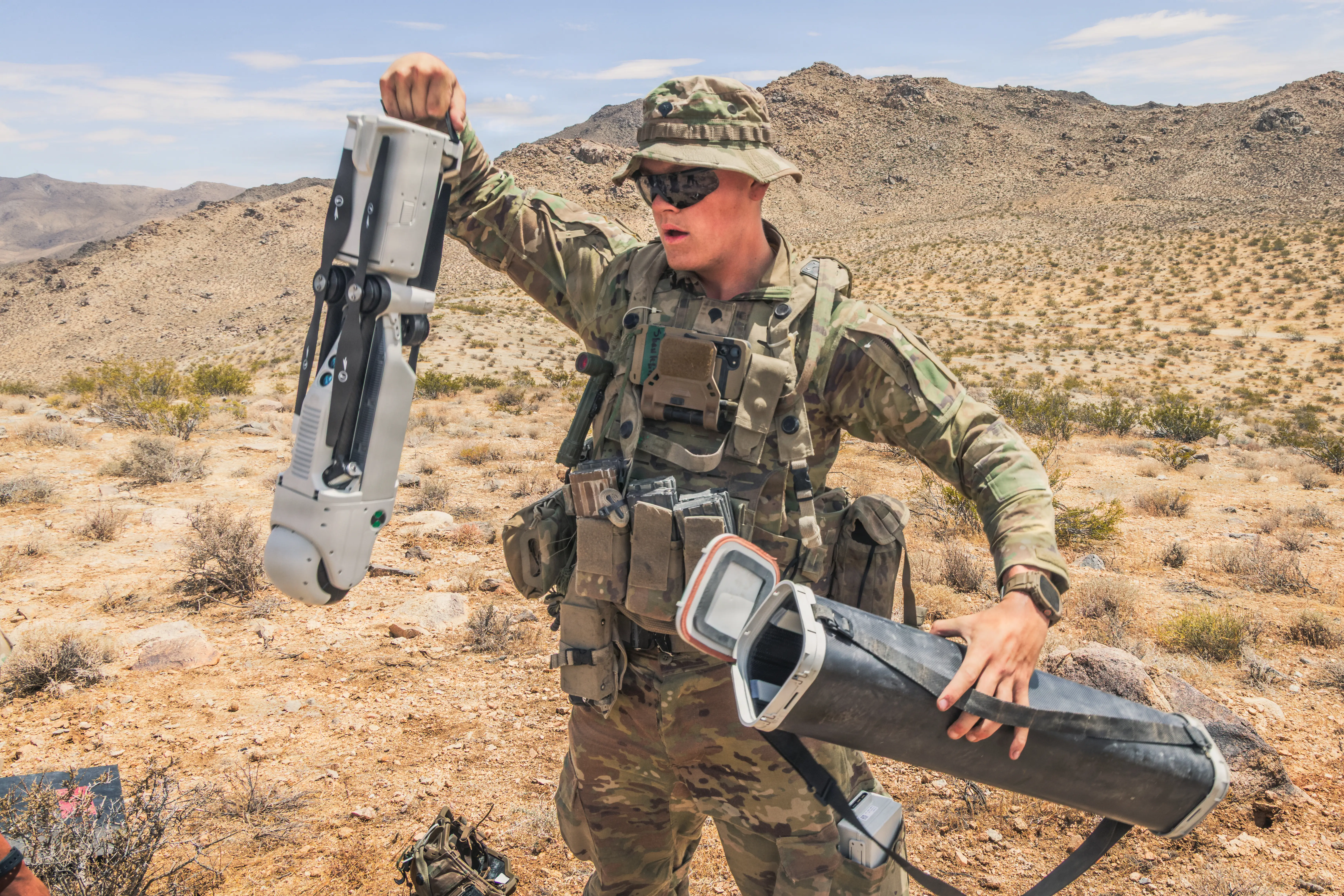 A US Army soldier pulls a drone out of its case in the desert.