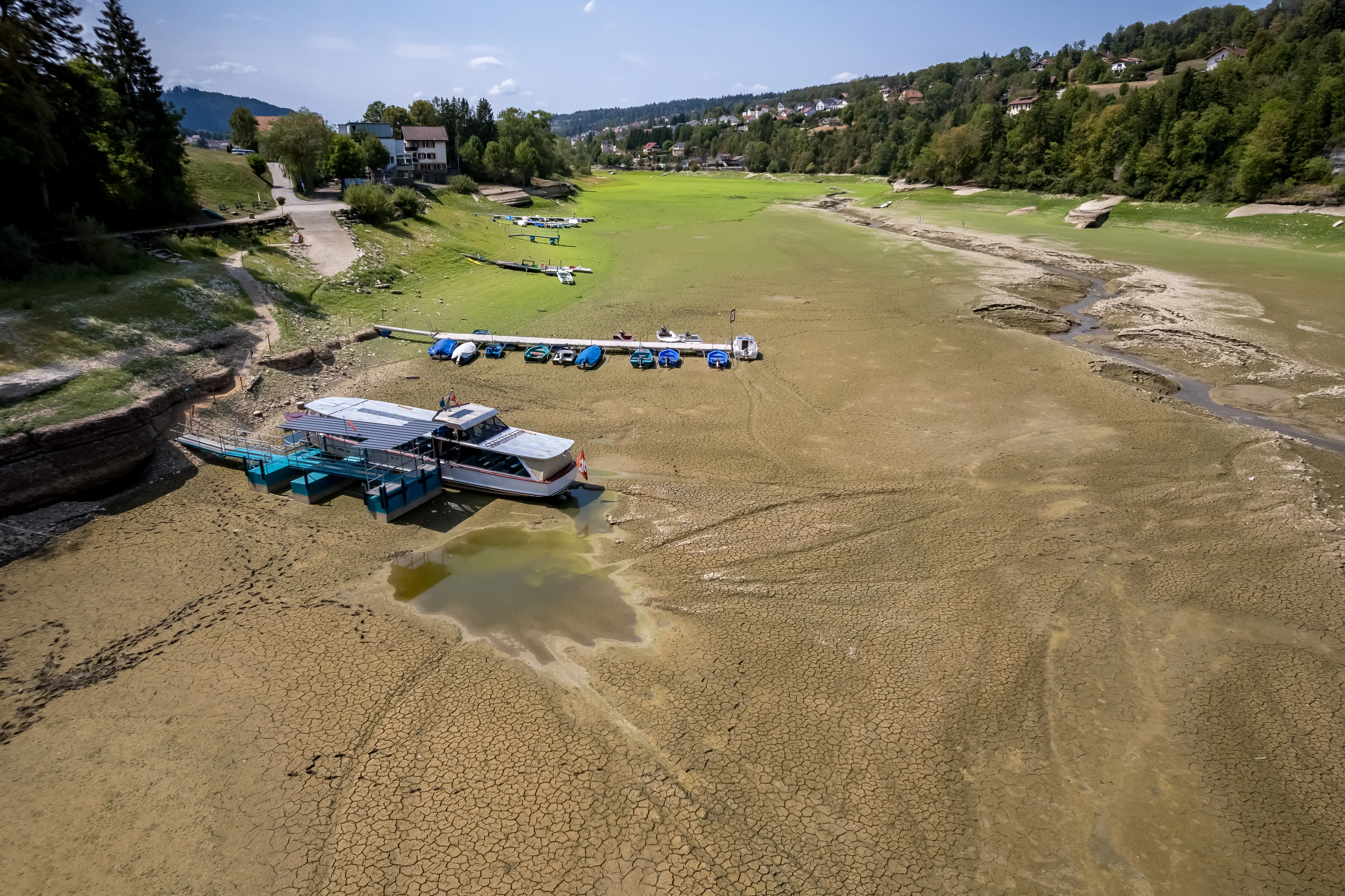 An aerial photograph of a nearly dry river with boats still docked.