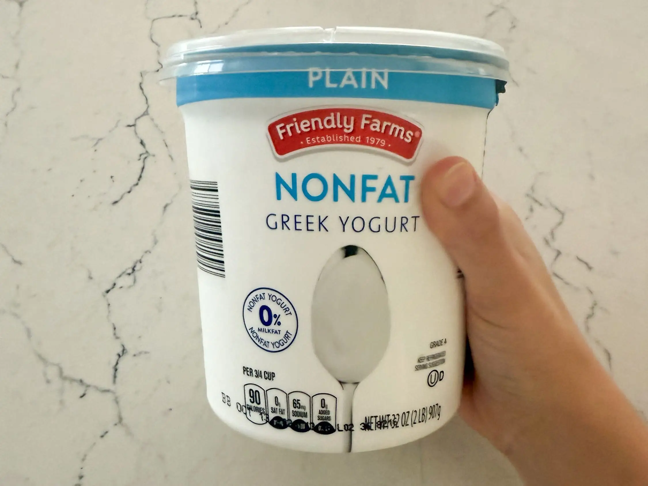 The writer is holding a container of Friendly Farms nonfat Greek yogurt.