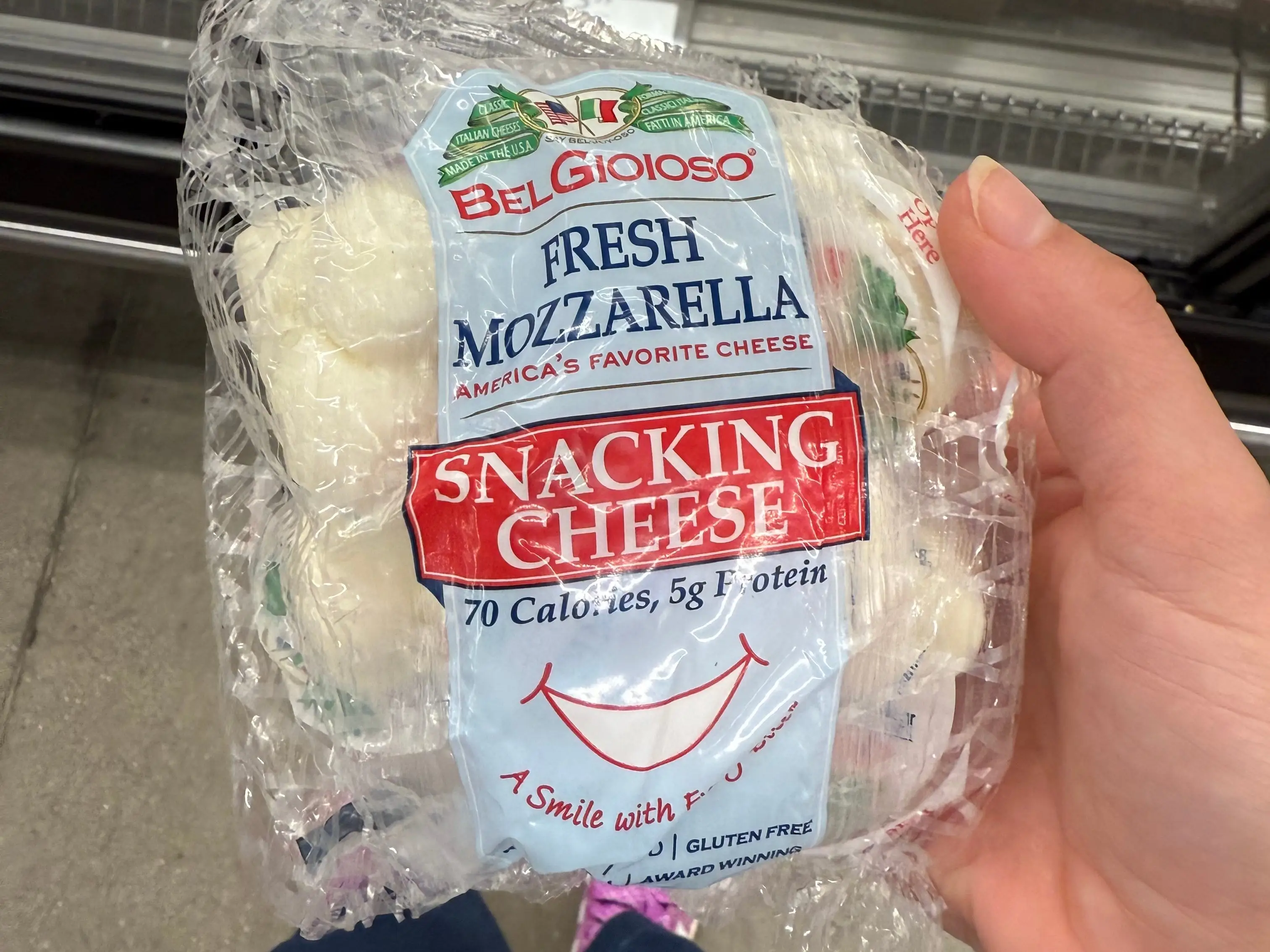 The writer is holding a package of BelGioioso fresh mozzarella snacking cheese at Aldi.