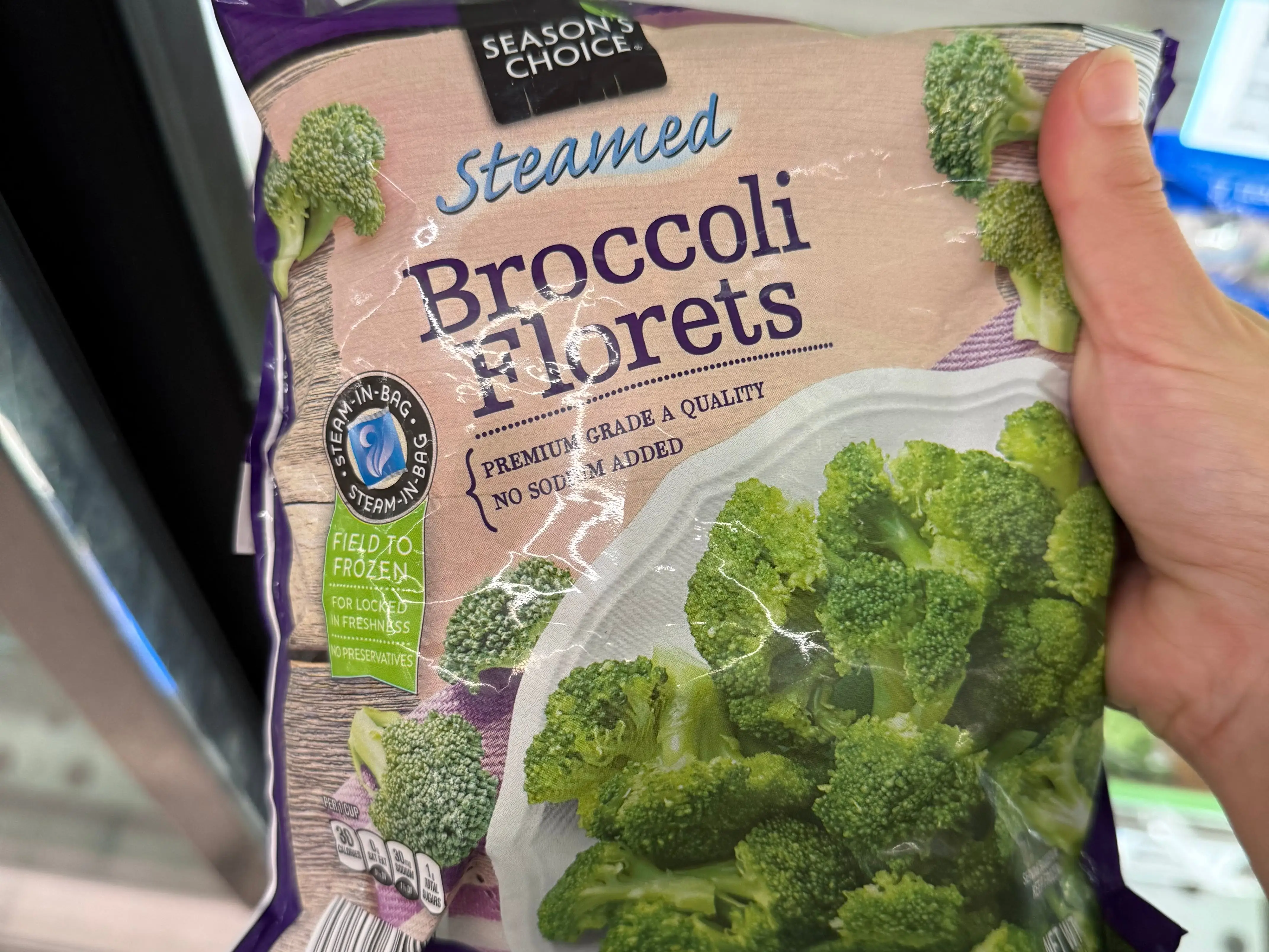 The writer holding a bag of Season's Choice steamed broccoli florets at Aldi.