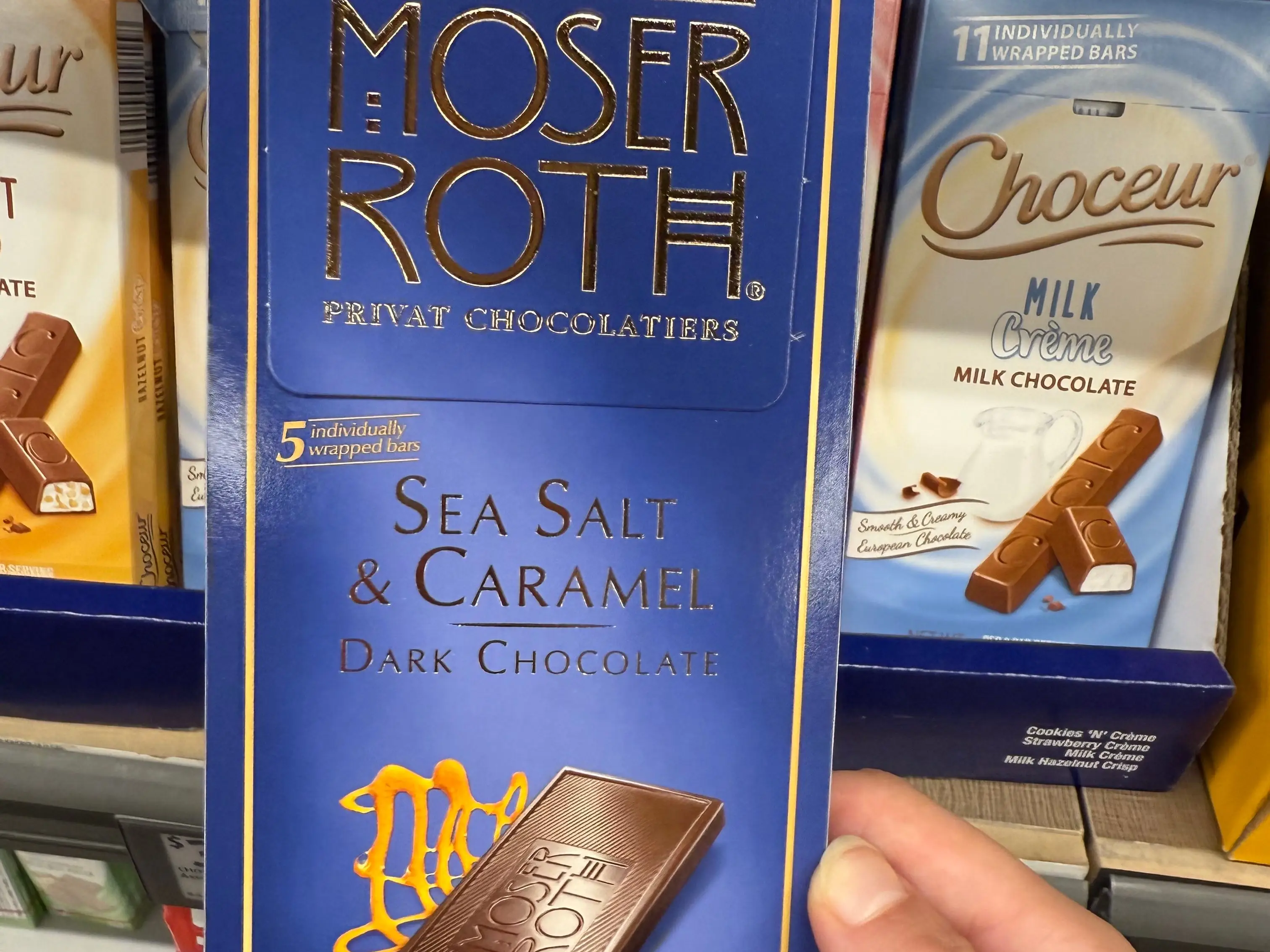 The writer is holding a Moser Roth chocolate bar at Aldi.