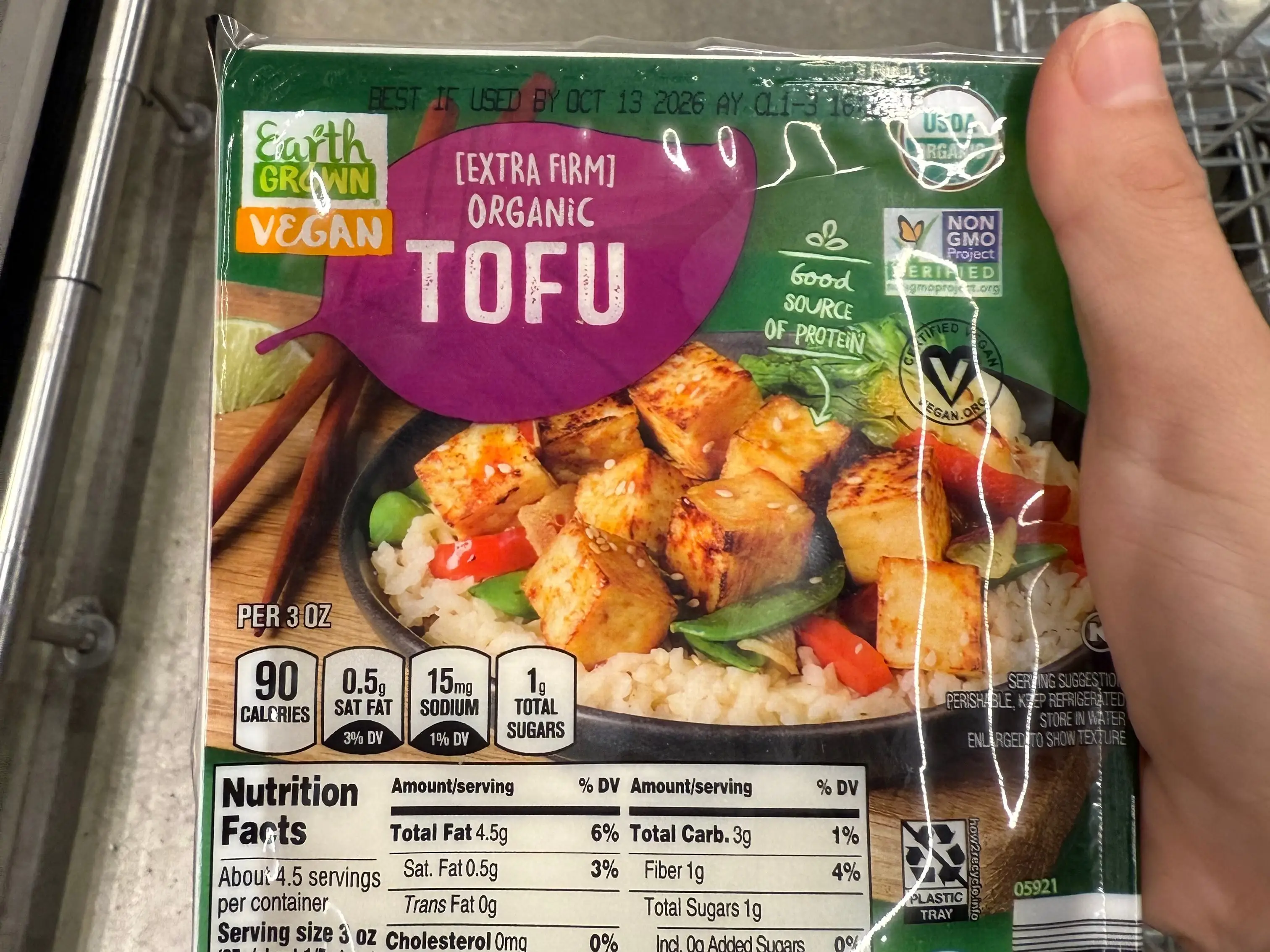 The writer is holding a container of Earth Grown extra-firm organic tofu at Aldi.