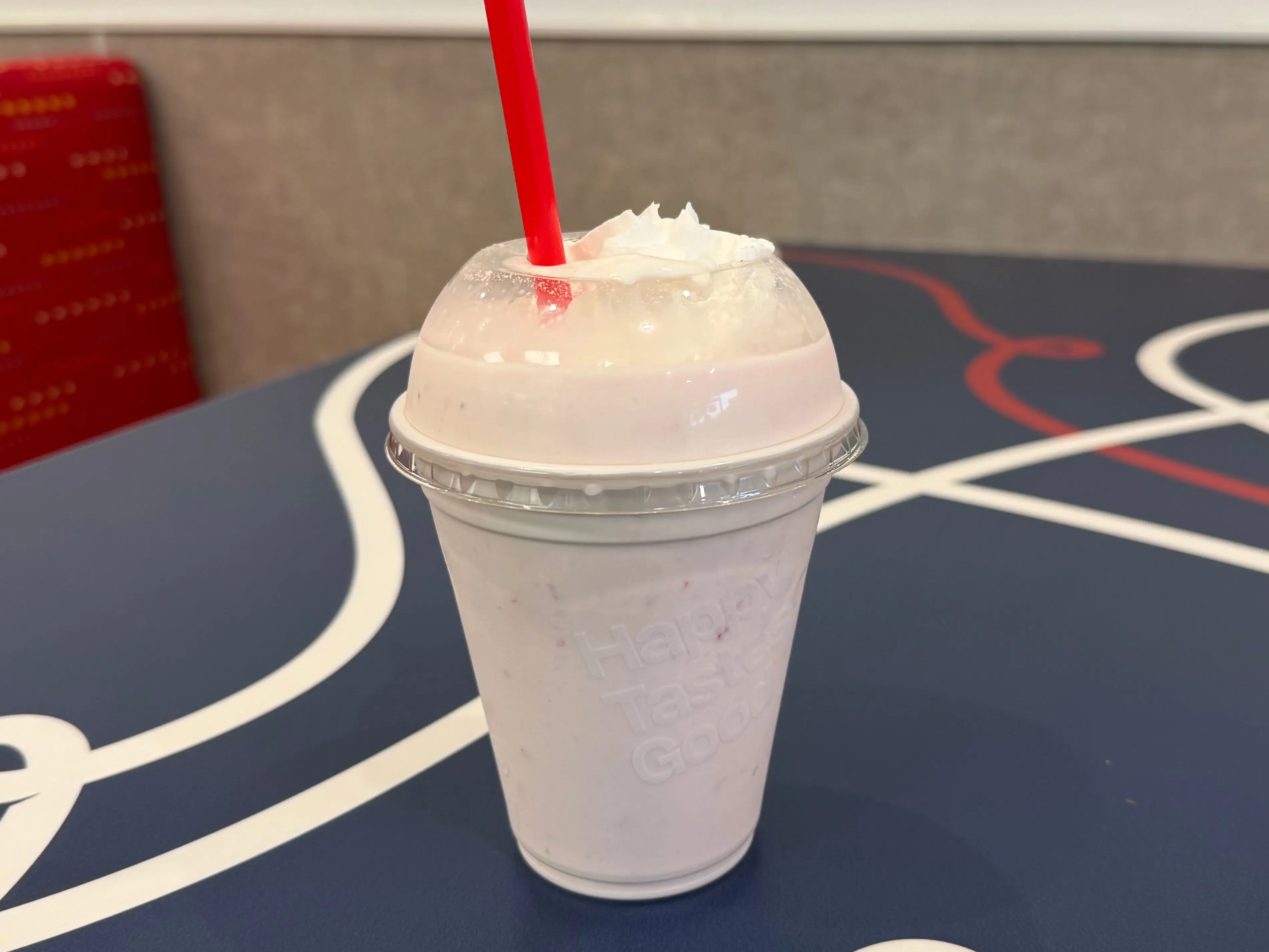A strawberry milkshake topped with whipped cream on a table.