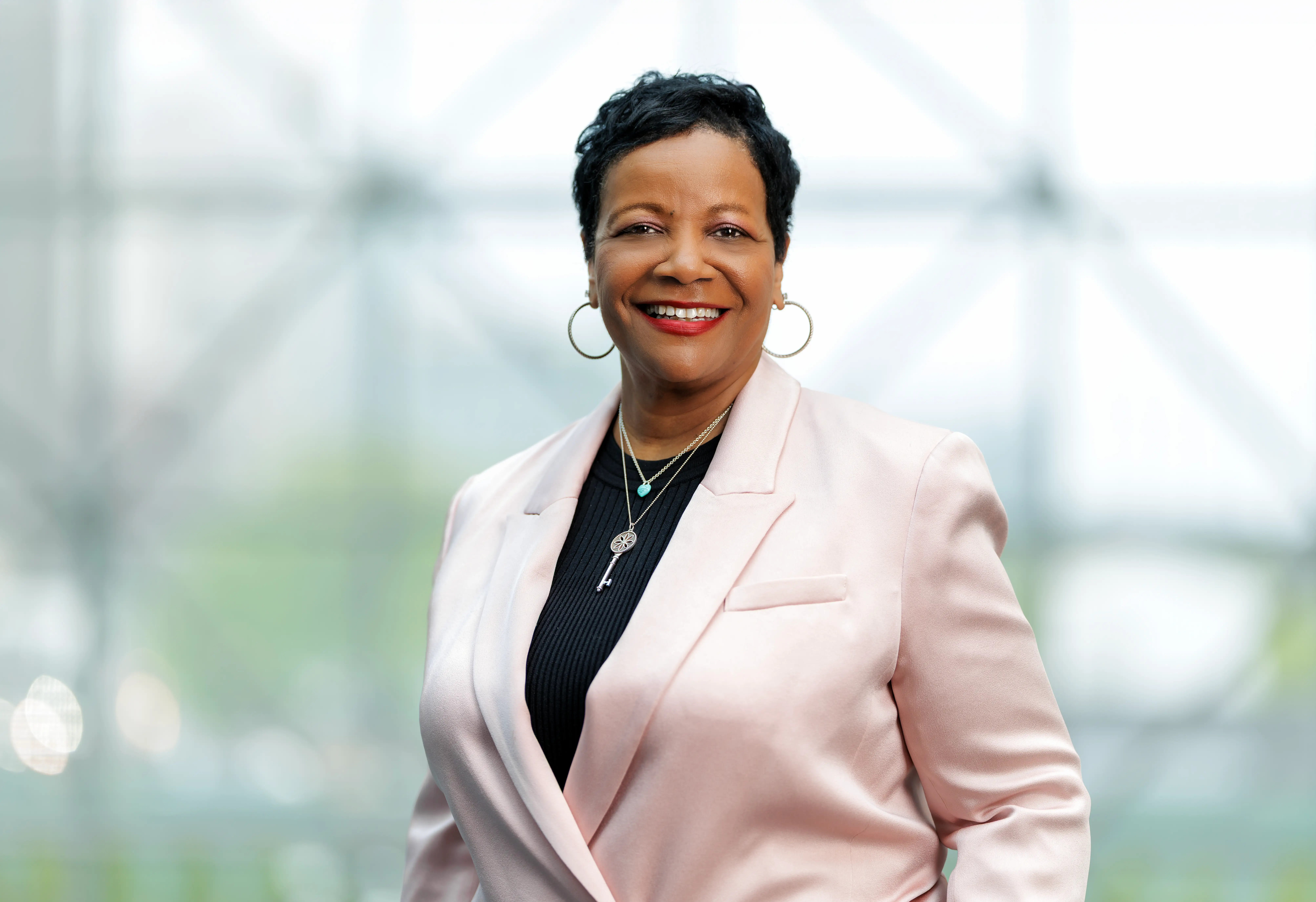 A woman CEO in a blazer with hoop earrings, smiling