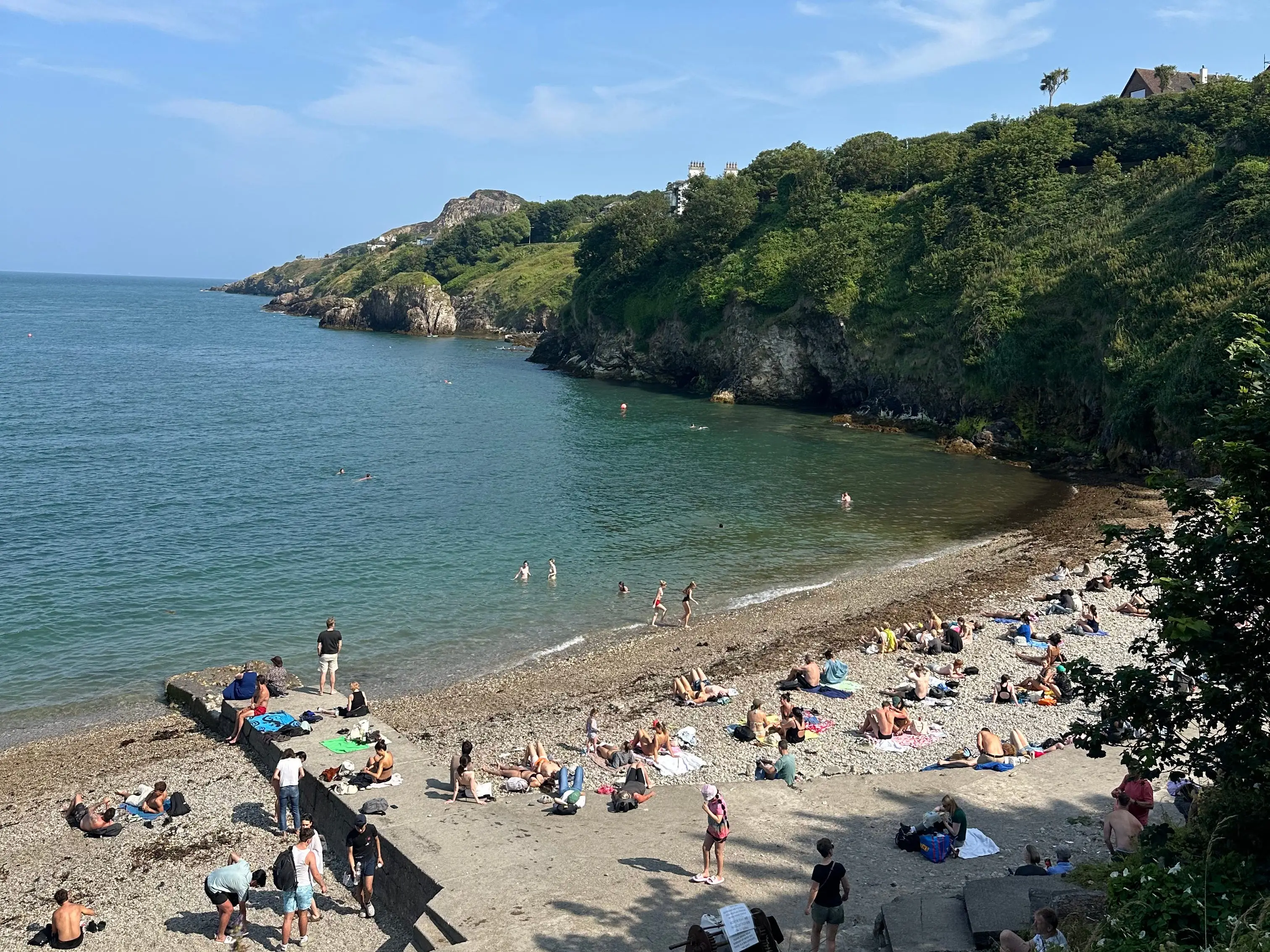 Beach in Howth, Ireland on a sunny day with people lying on the sand.