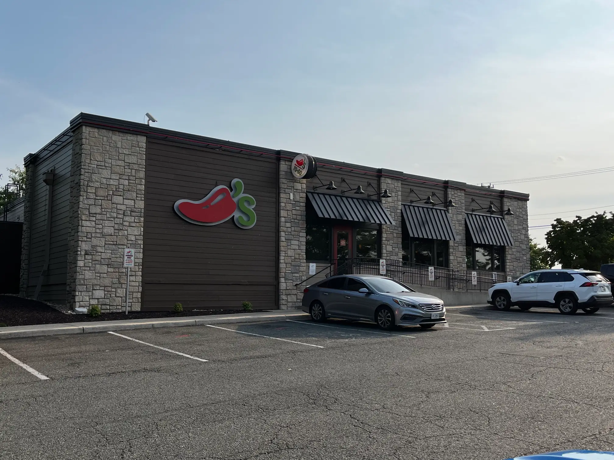 A Chili's restaurant exterior with branded signage, striped awnings, and parked cars in a lot.