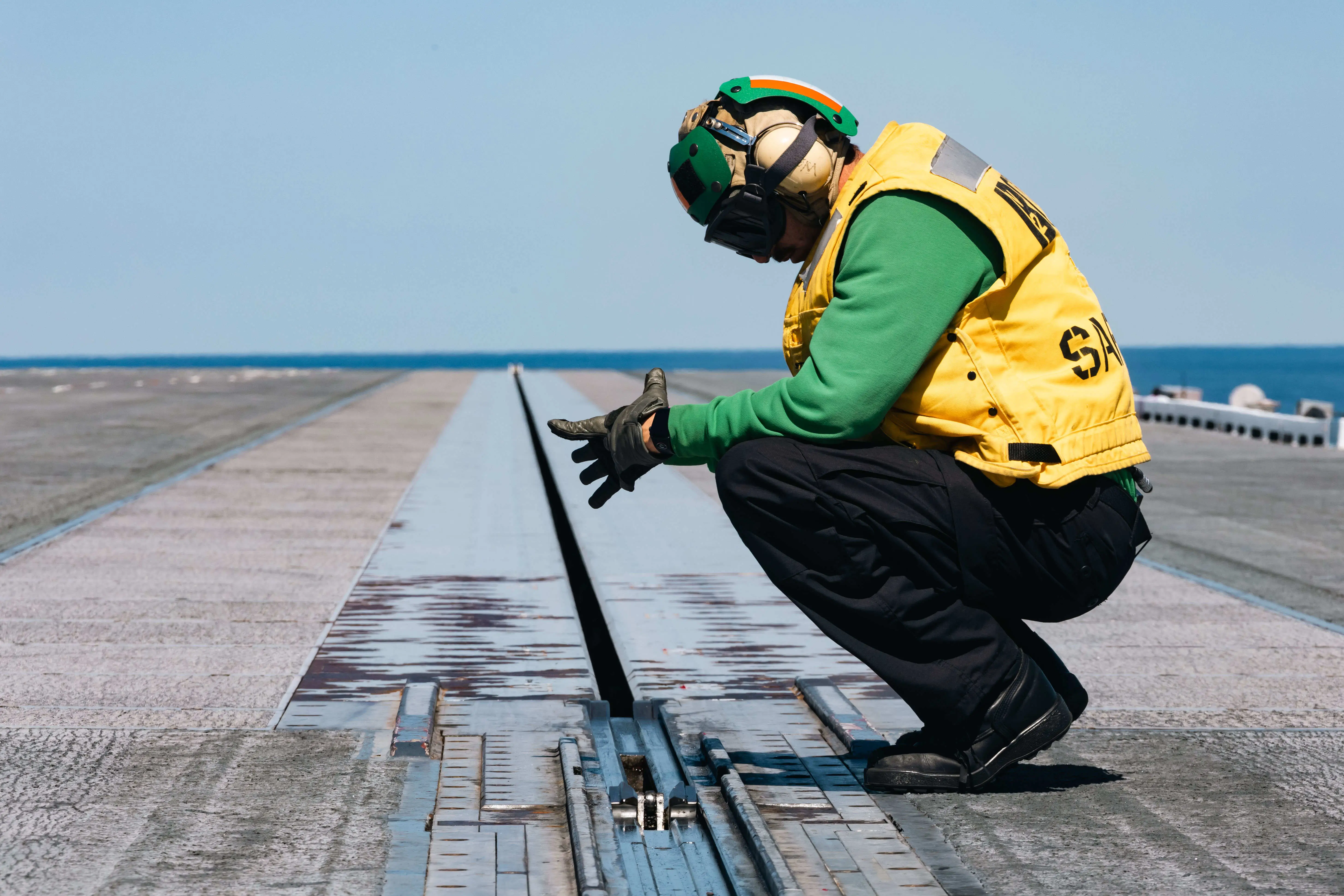 A man stands next to the electromagnetic aircraft launch system on the USS Gerald R. Ford.