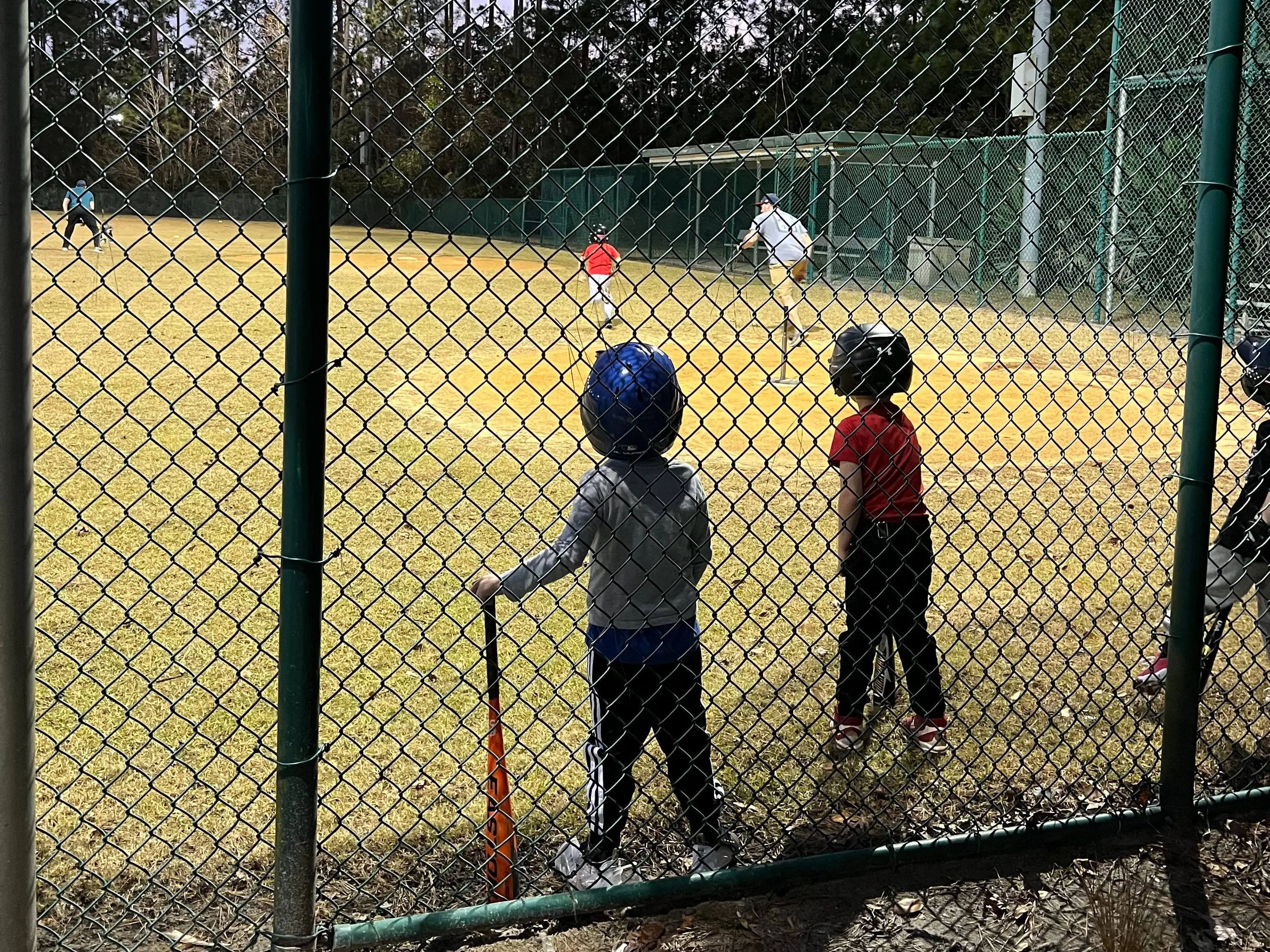 Two boys stand near home plate at a t-ball game.