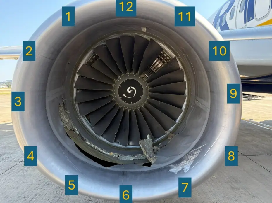 Damaged aircraft jet engine with exposed fan blades and numbered inspection labels on an airport apron.