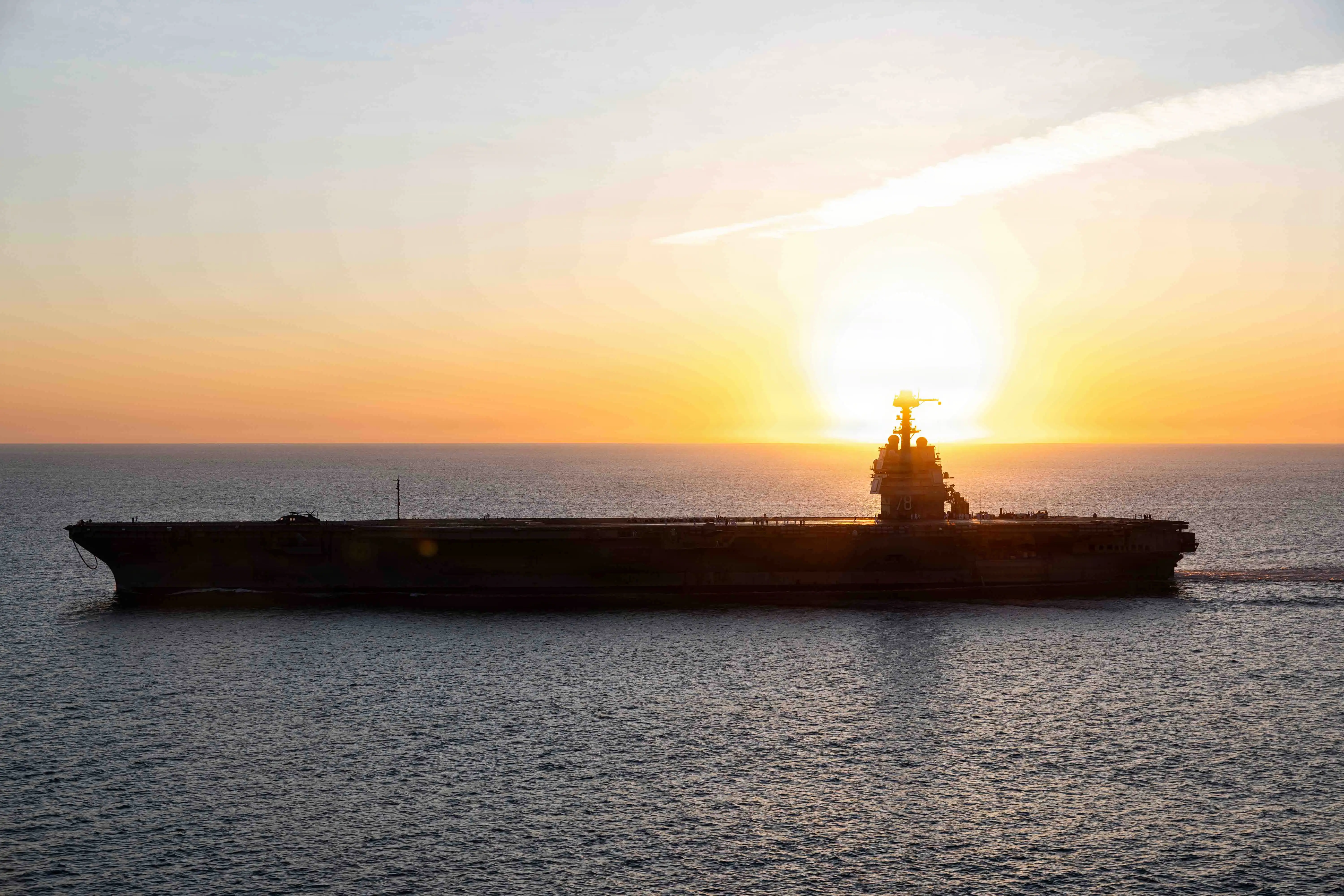 The USS Gerald R. Ford aircraft carrier sails at sunset.