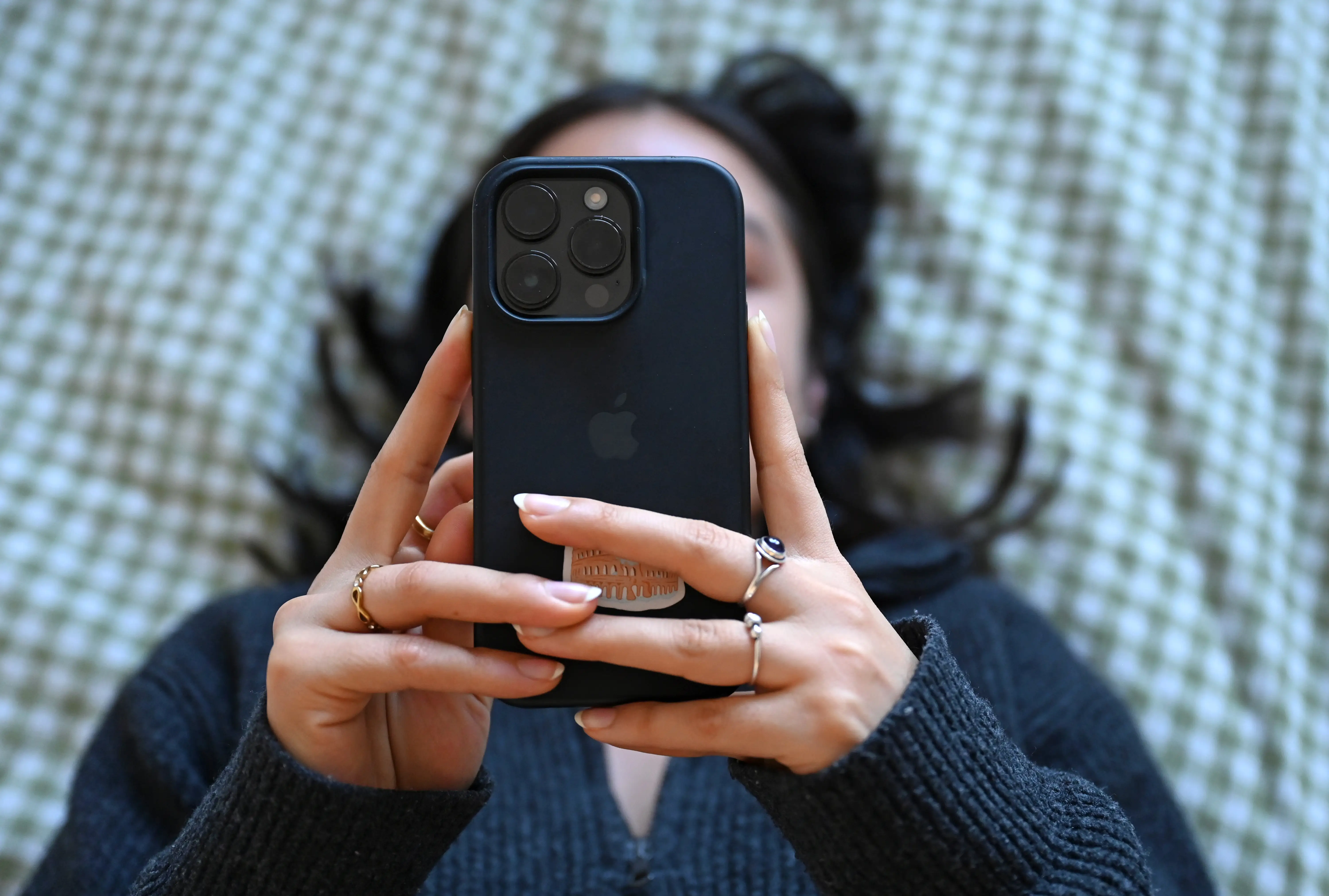 A young woman lies on the bed with a smartphone in her hand