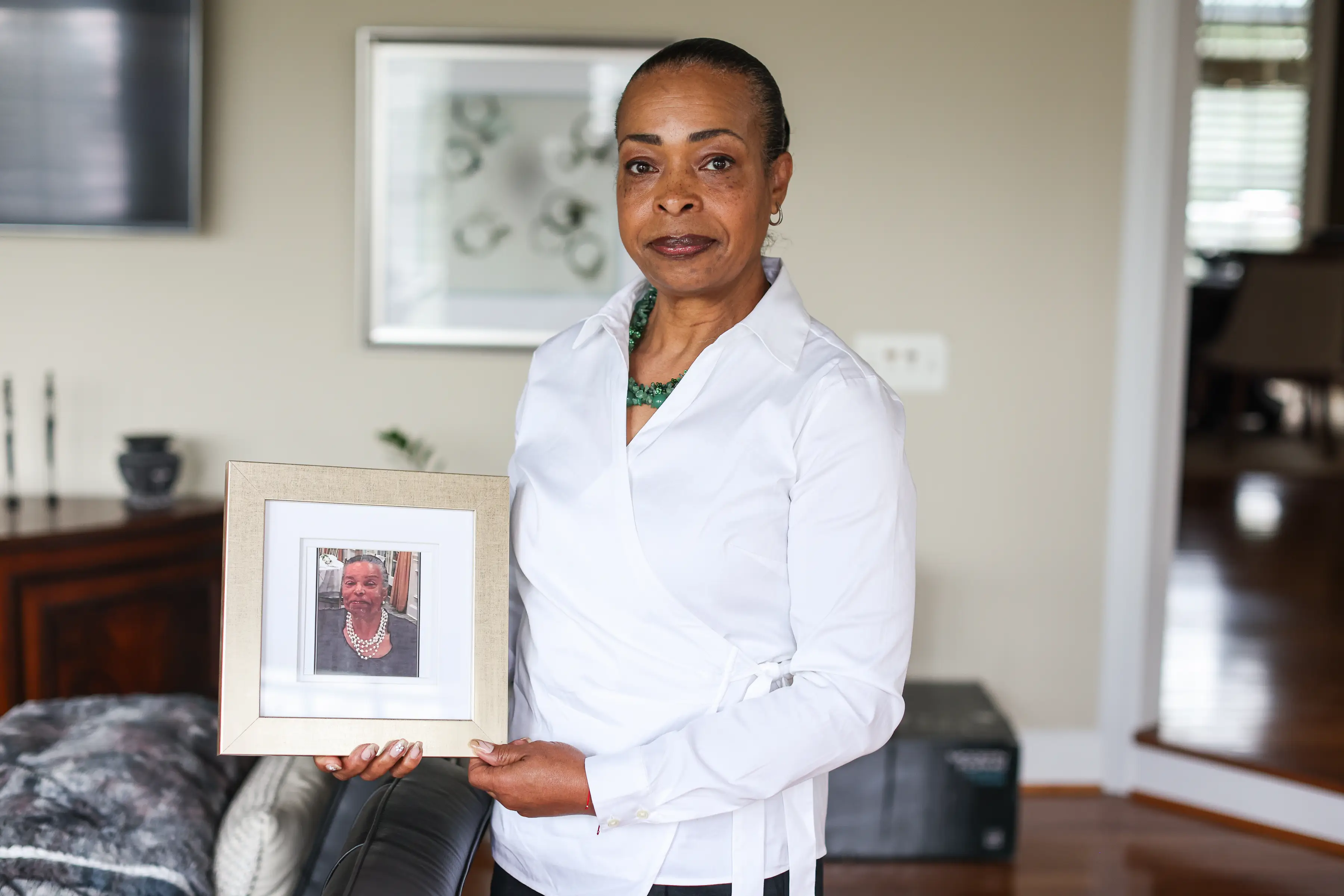 Tamara Johnson, 58, holds a framed photo of her mother at her home in Leesburg, Virginia, on July 10, 2026.
