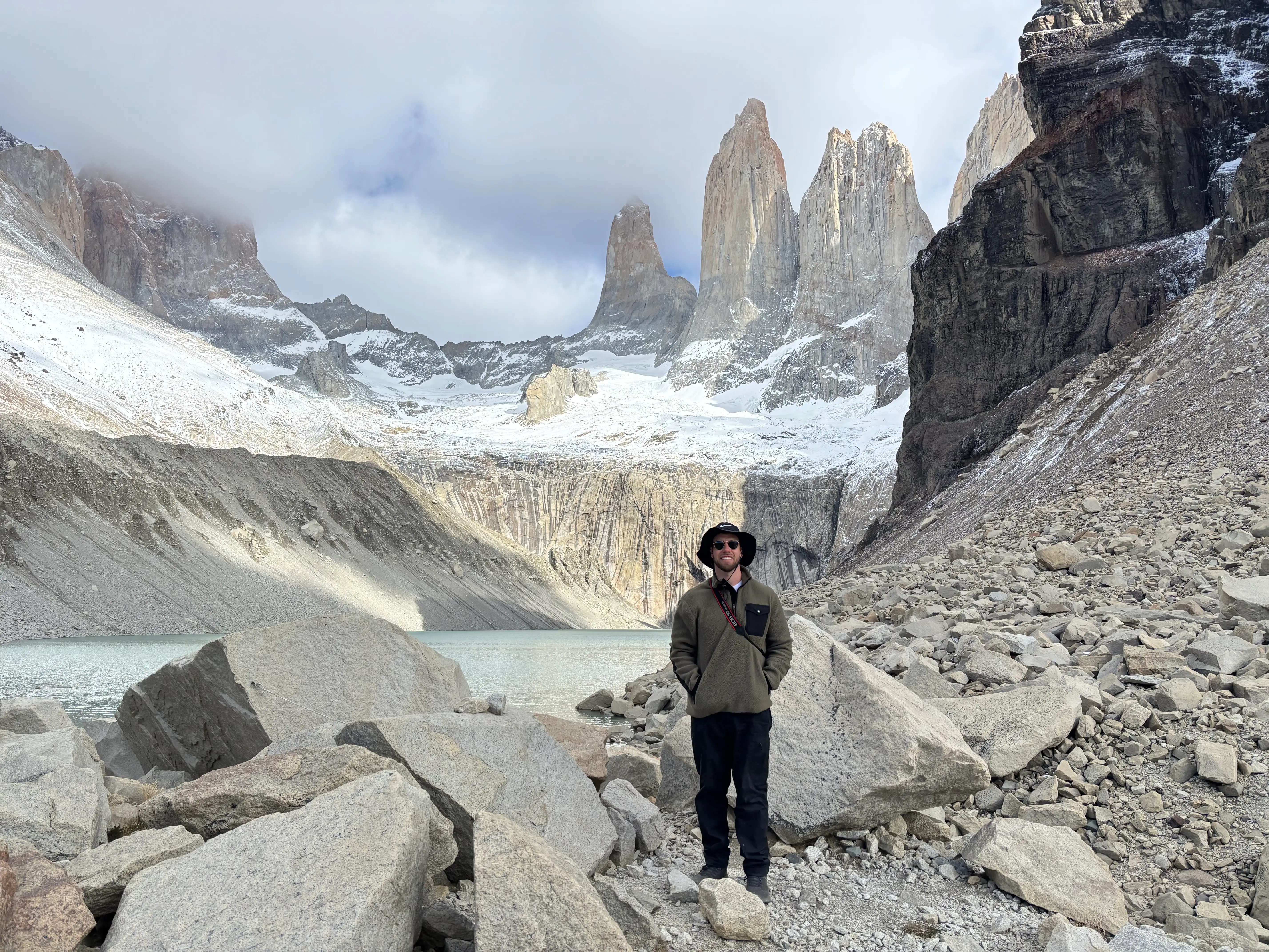 Alex Harman stands among rocks beside a glacial lake below the Torres del Paine peaks.