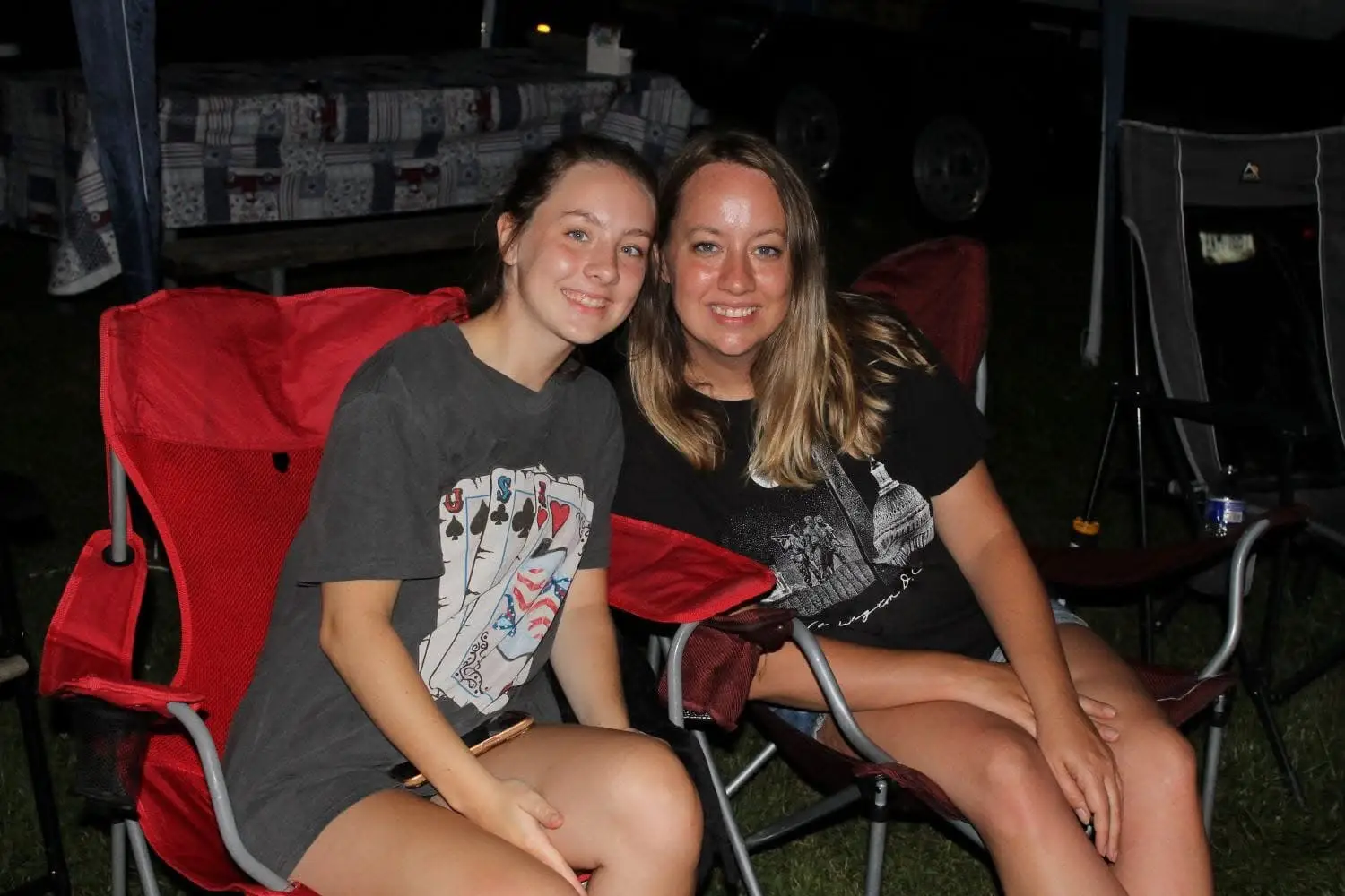 The author and her daughter pose while sitting in camping chairs outside at night.