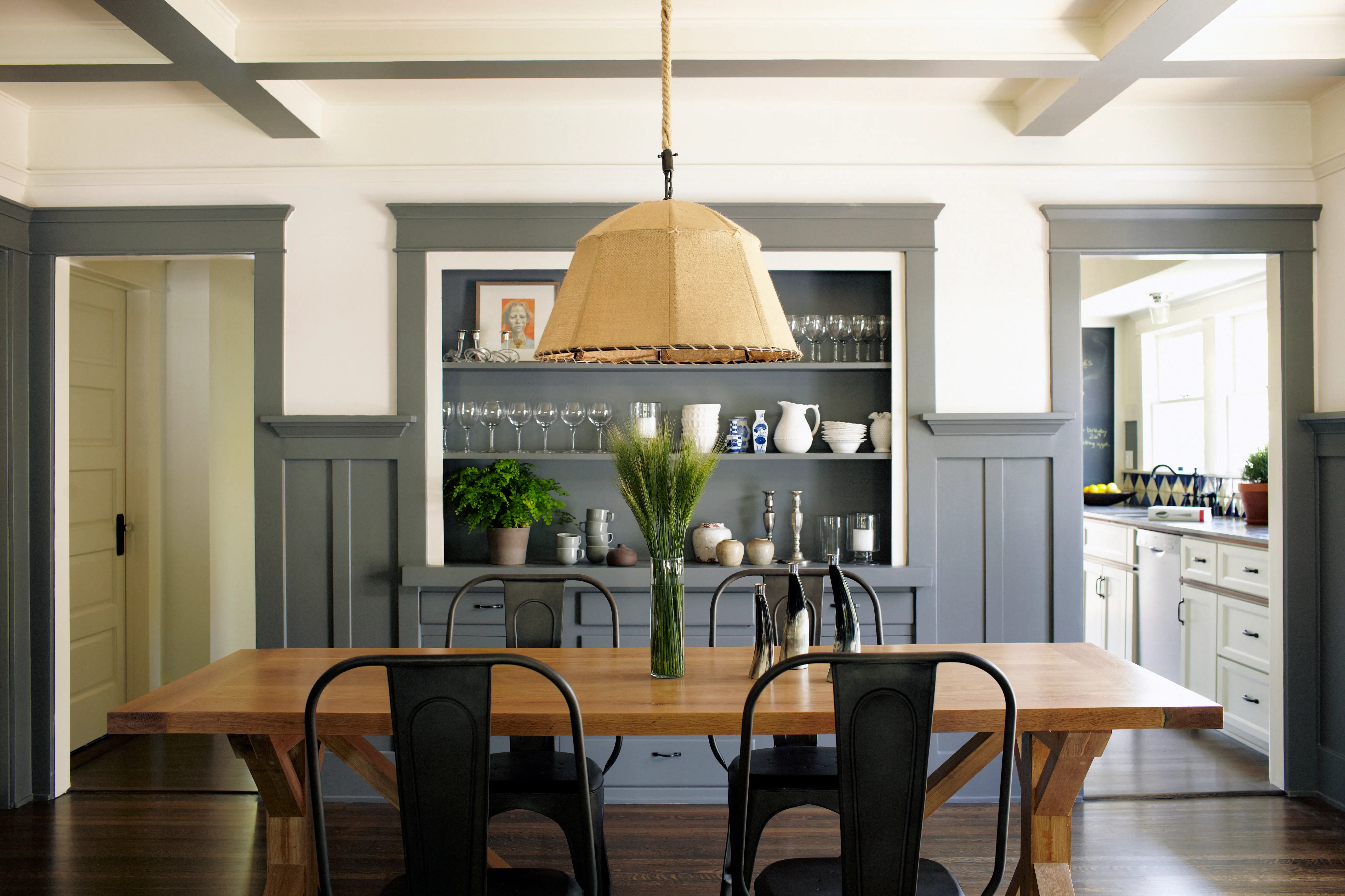 Living room area with open shelving in blue-gray shade, wood table, pendant light