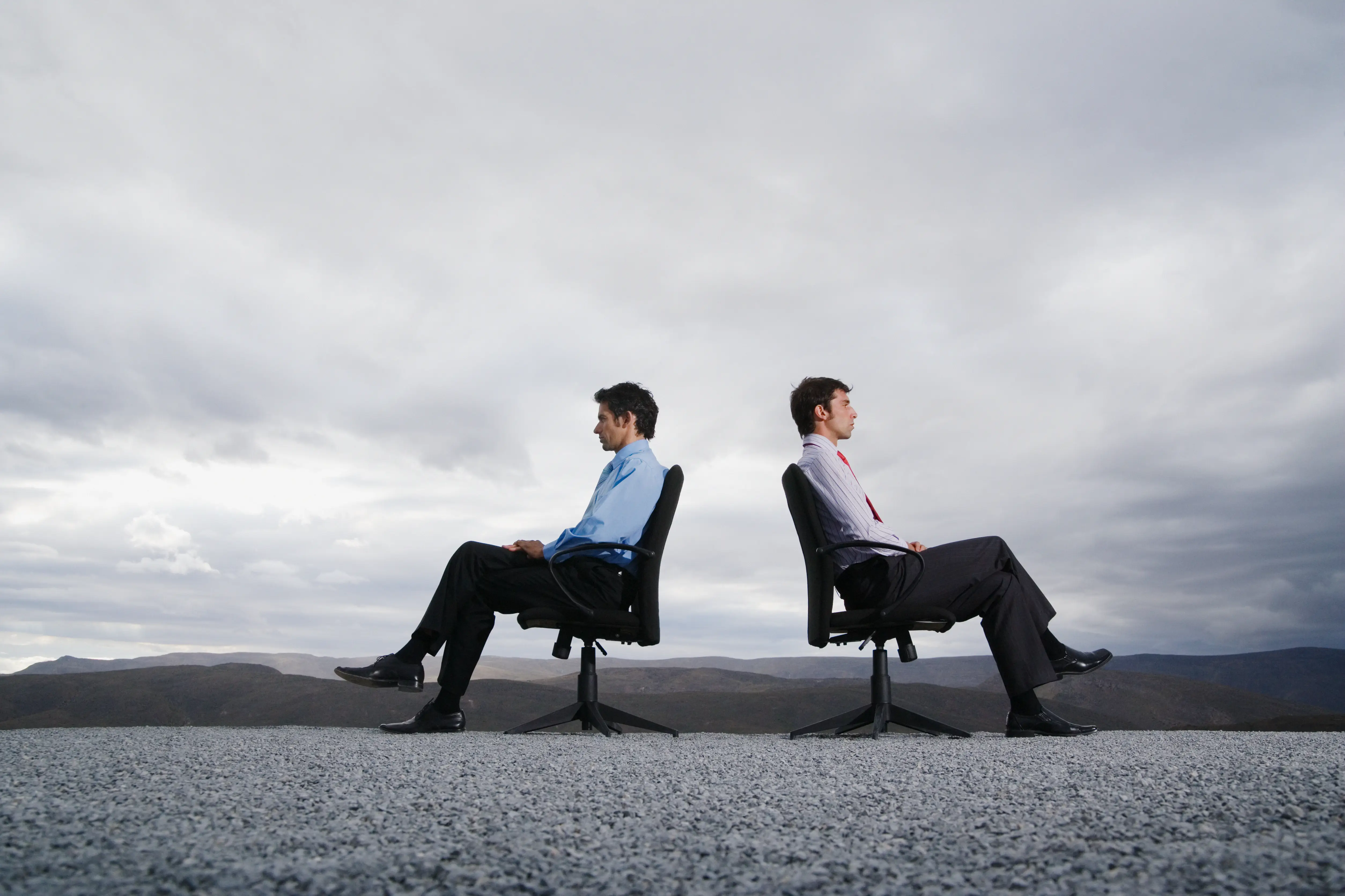Two office workers in chairs facing away from each other.