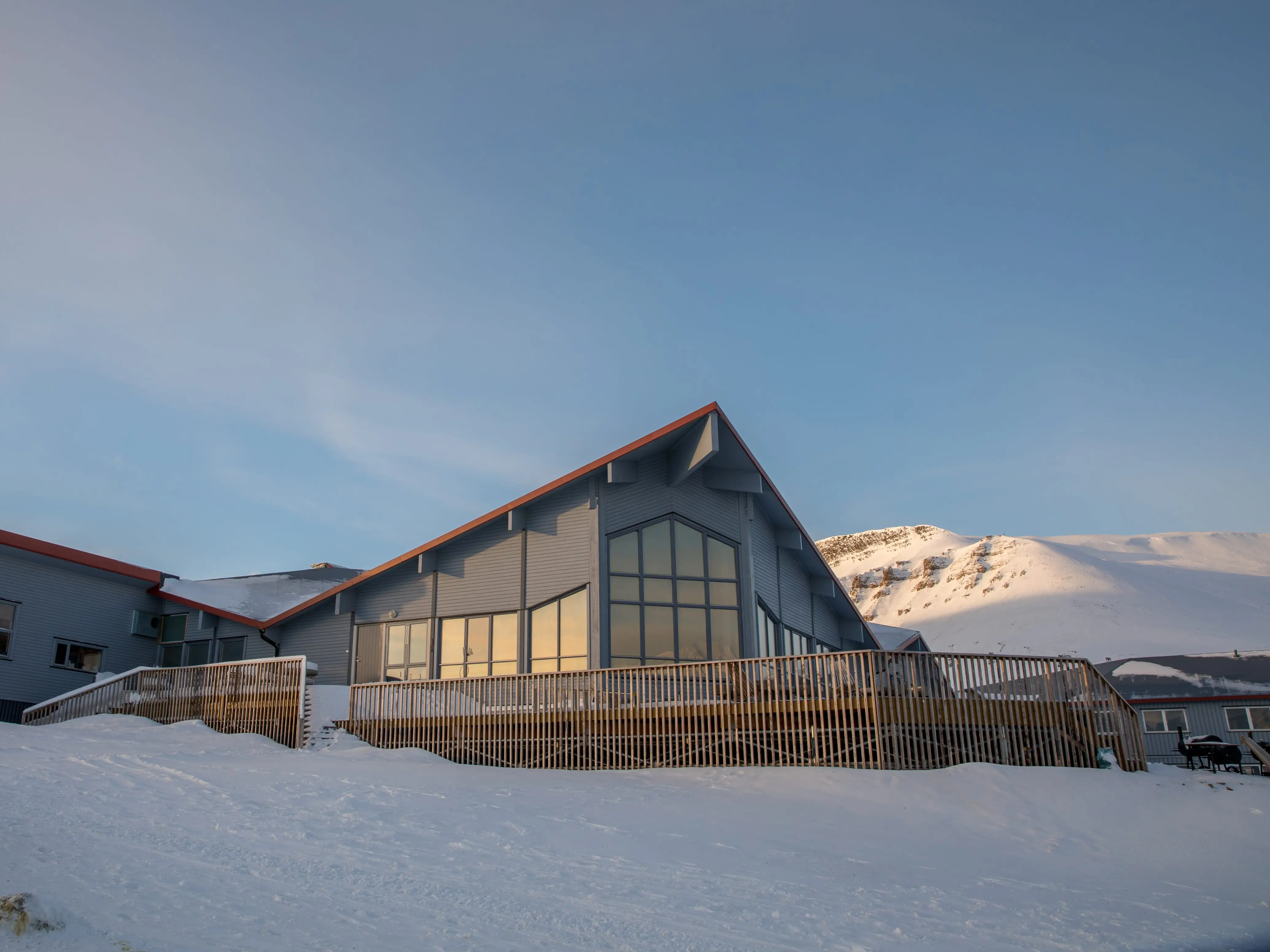 The Radisson Blu Polar Hotel Spitsbergen in Longyearbyen. Exterior in winter light, with snow and mountains in the background.