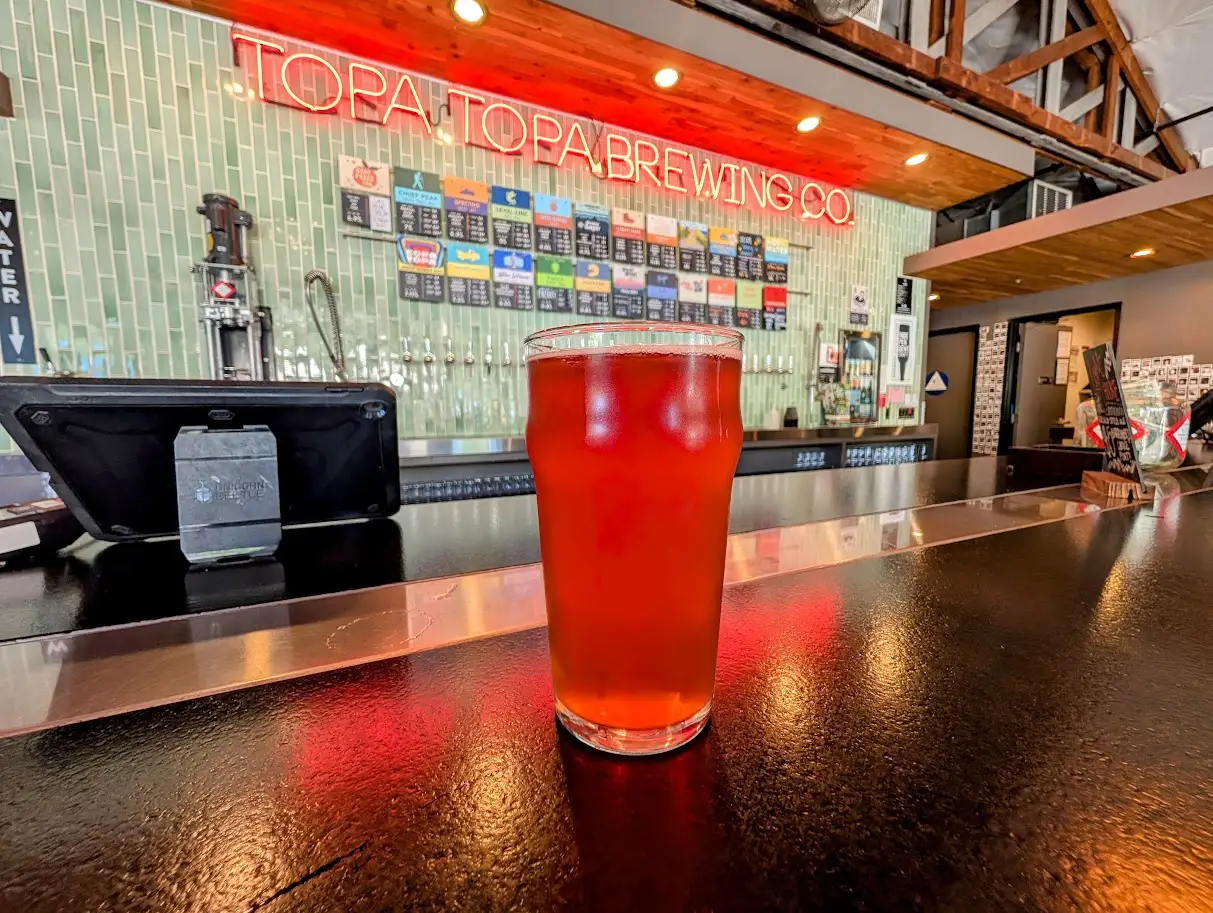 Red drink on counter in front of Topa brewing menu/beer wall