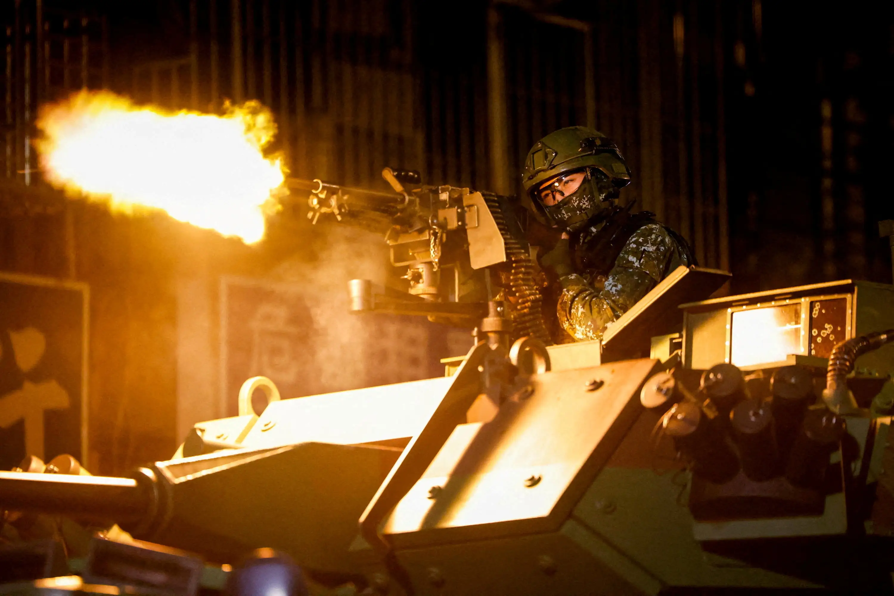 A masked Taiwanese soldier opens fire on a mounted machine gun.