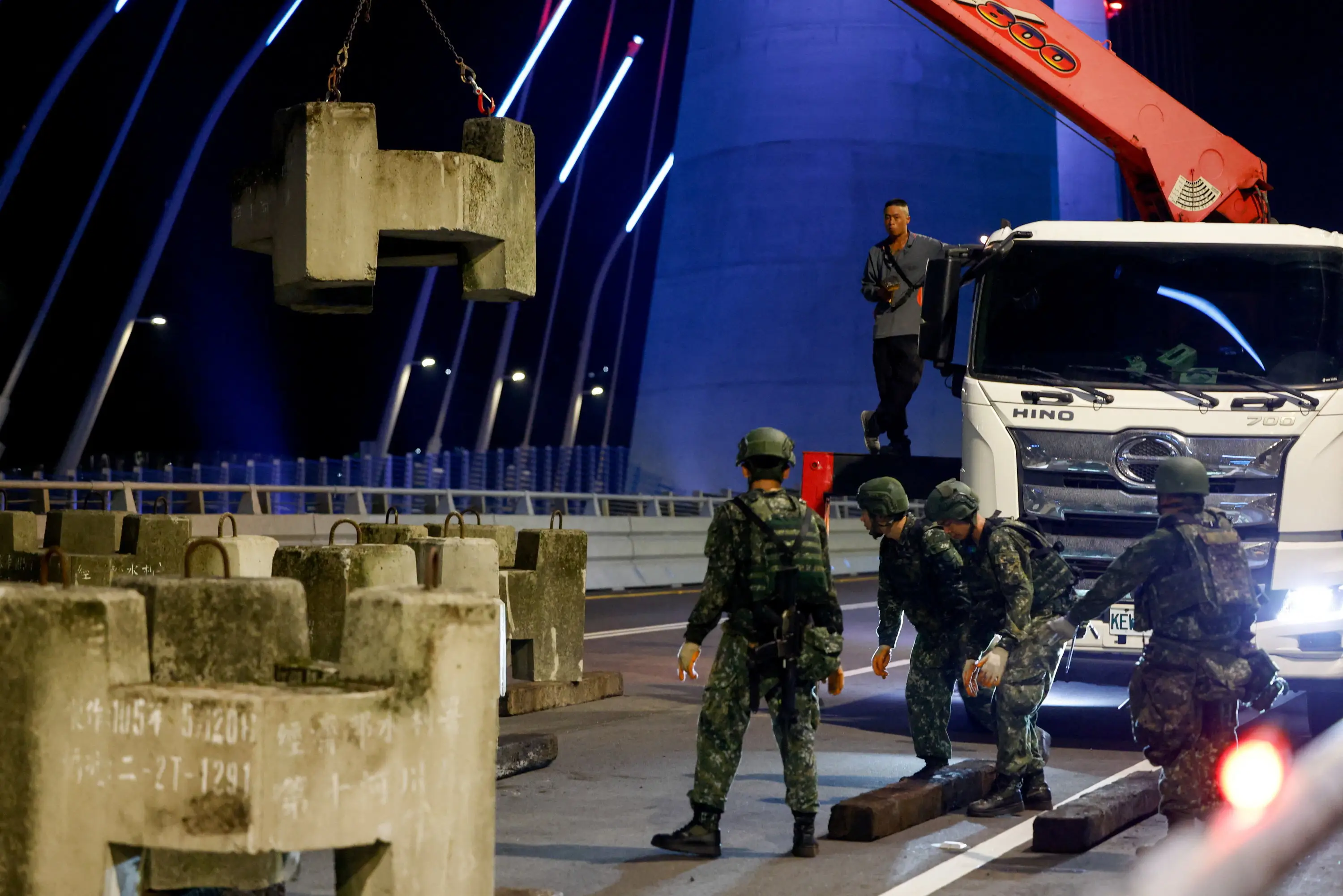 Taiwanese soldiers prepare to receive a concrete block lifted by a crane.