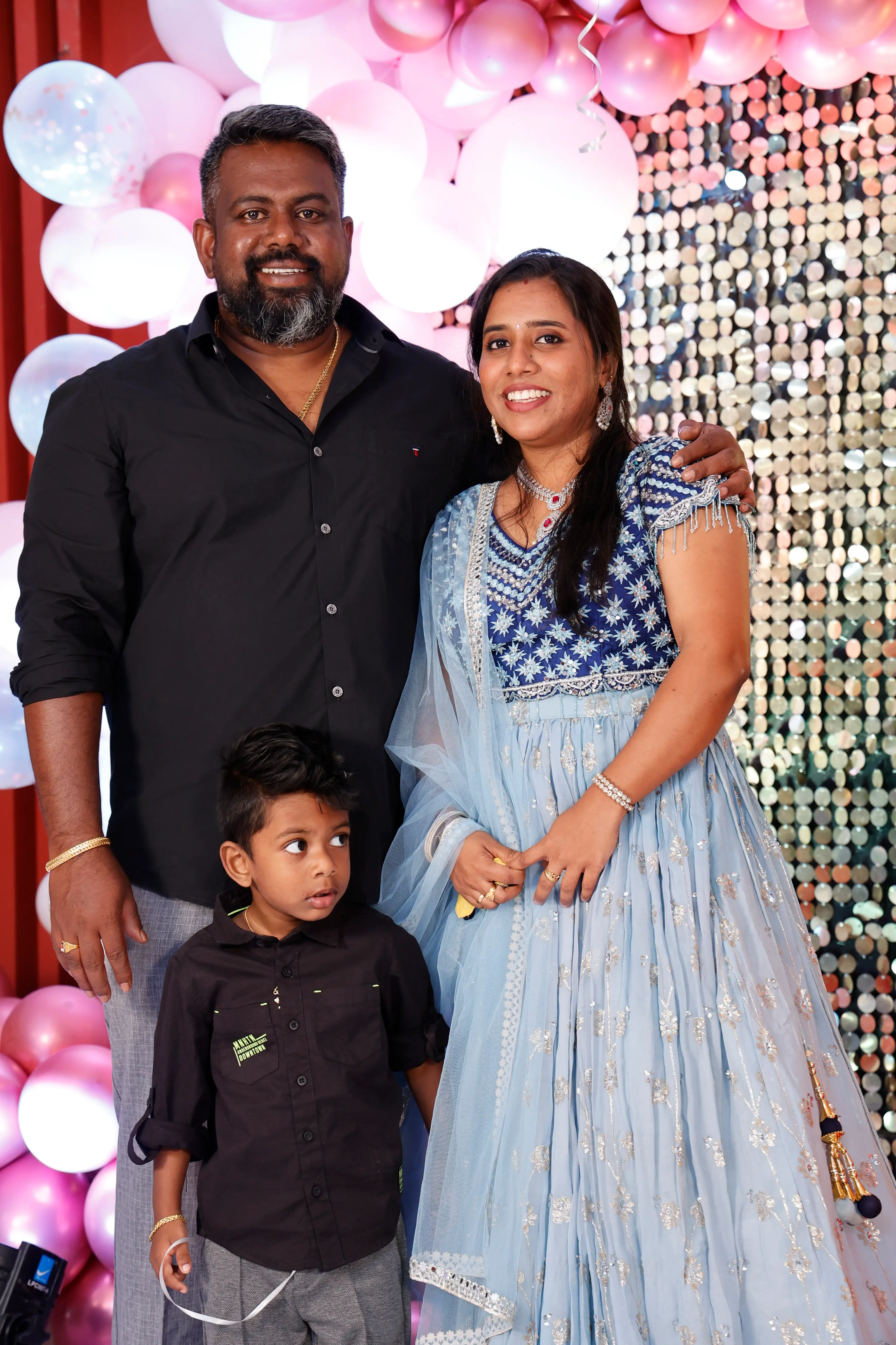 Chinnam is standing with her husband and son, wearing a blue outfit.
