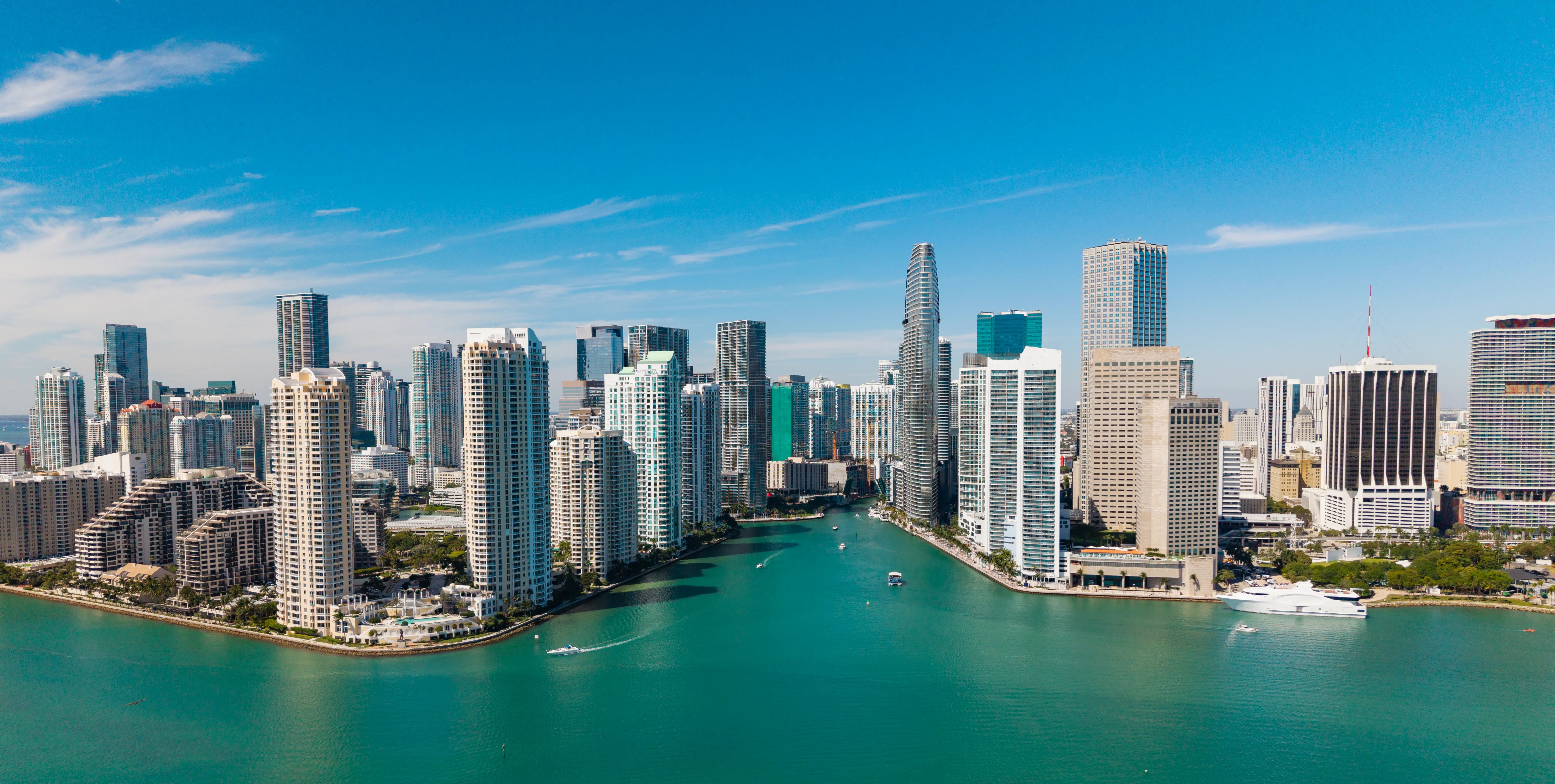 Downtown Miami skyline rises along a turquoise waterfront under a clear blue sky.