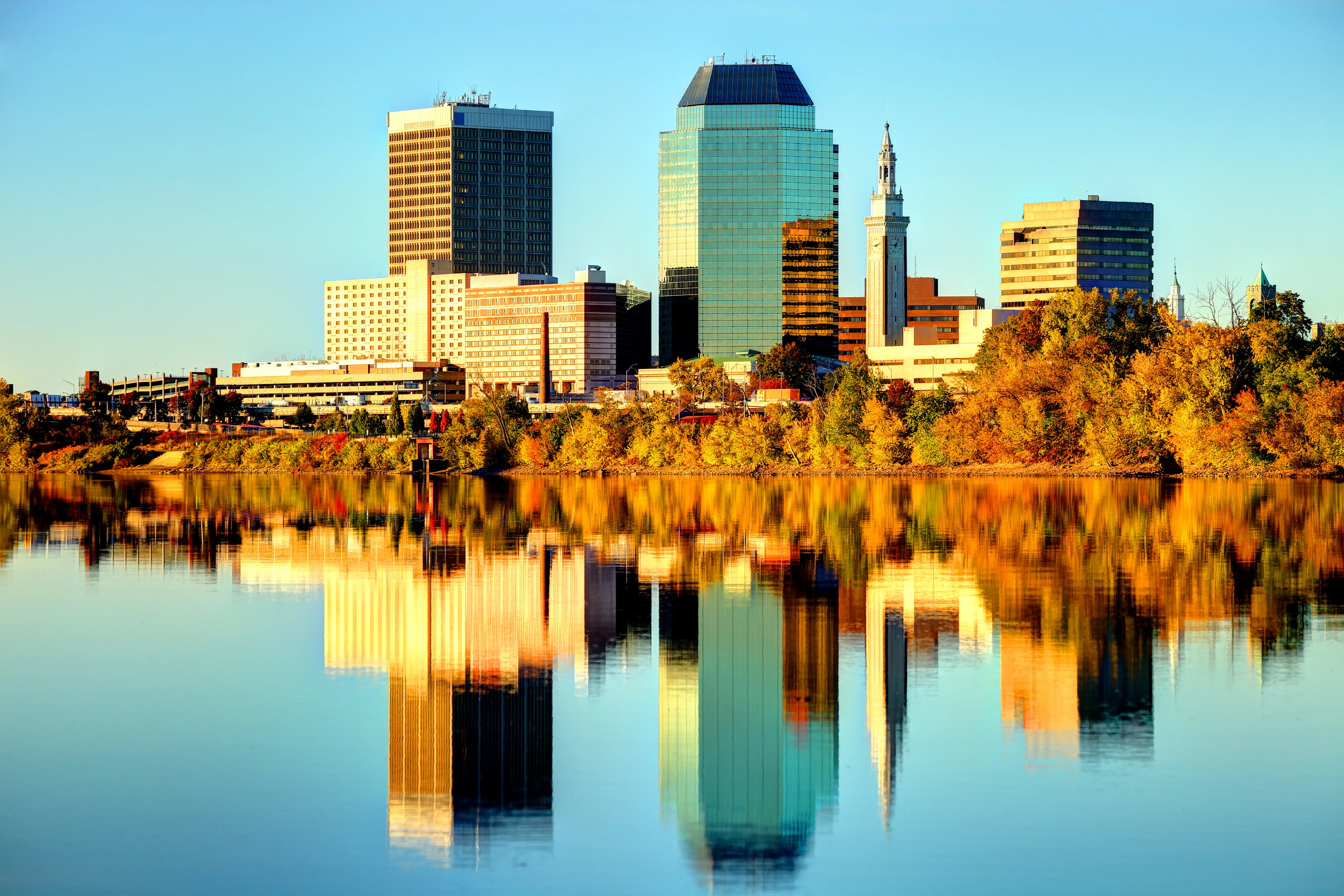 Downtown Springfield skyline reflects in a calm river under warm golden light.