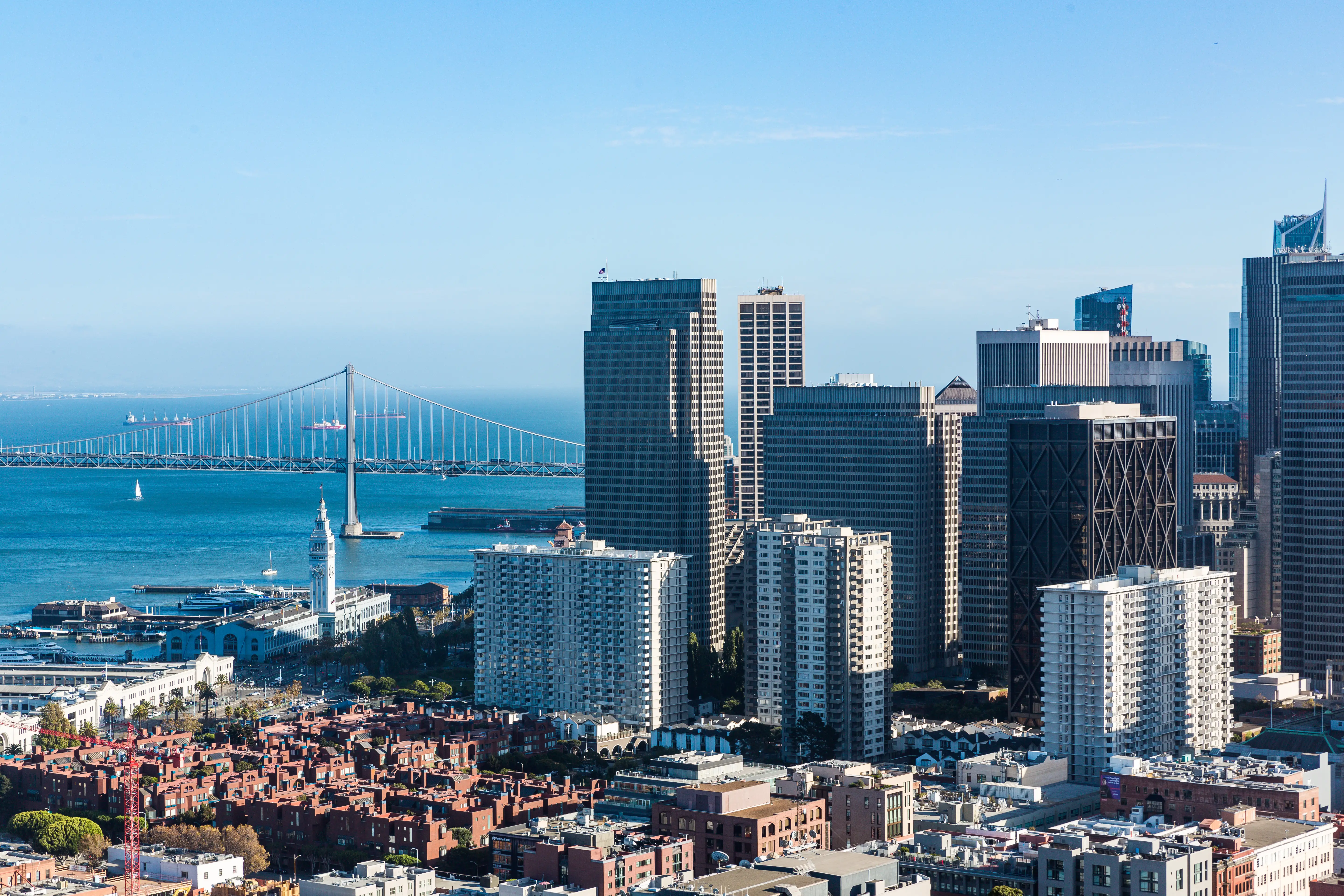 San Francisco skyline with high-rise buildings, the Ferry Building, and the Bay Bridge across the bay.