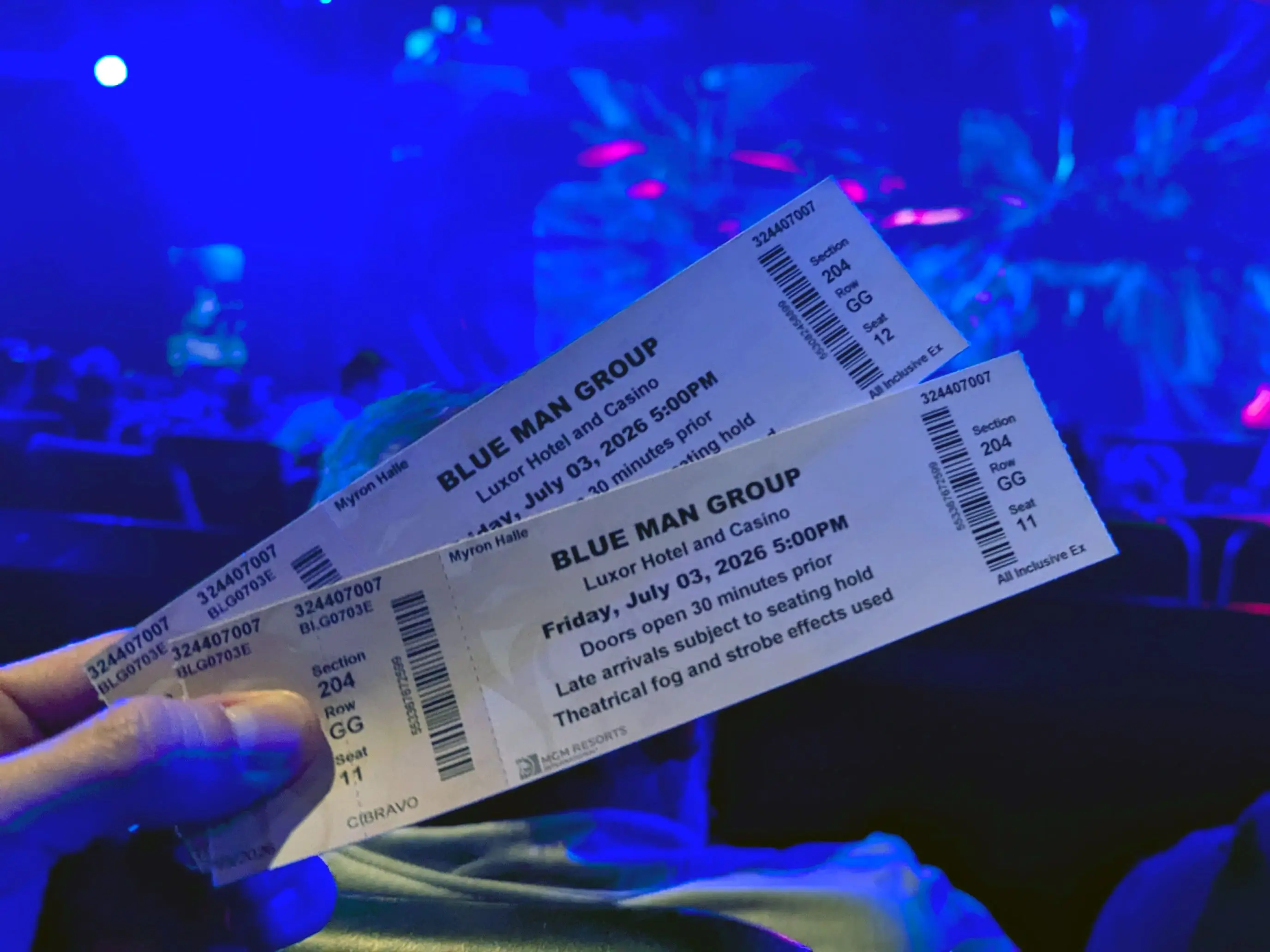 A hand holding two tickets to the Blue Man Group show.