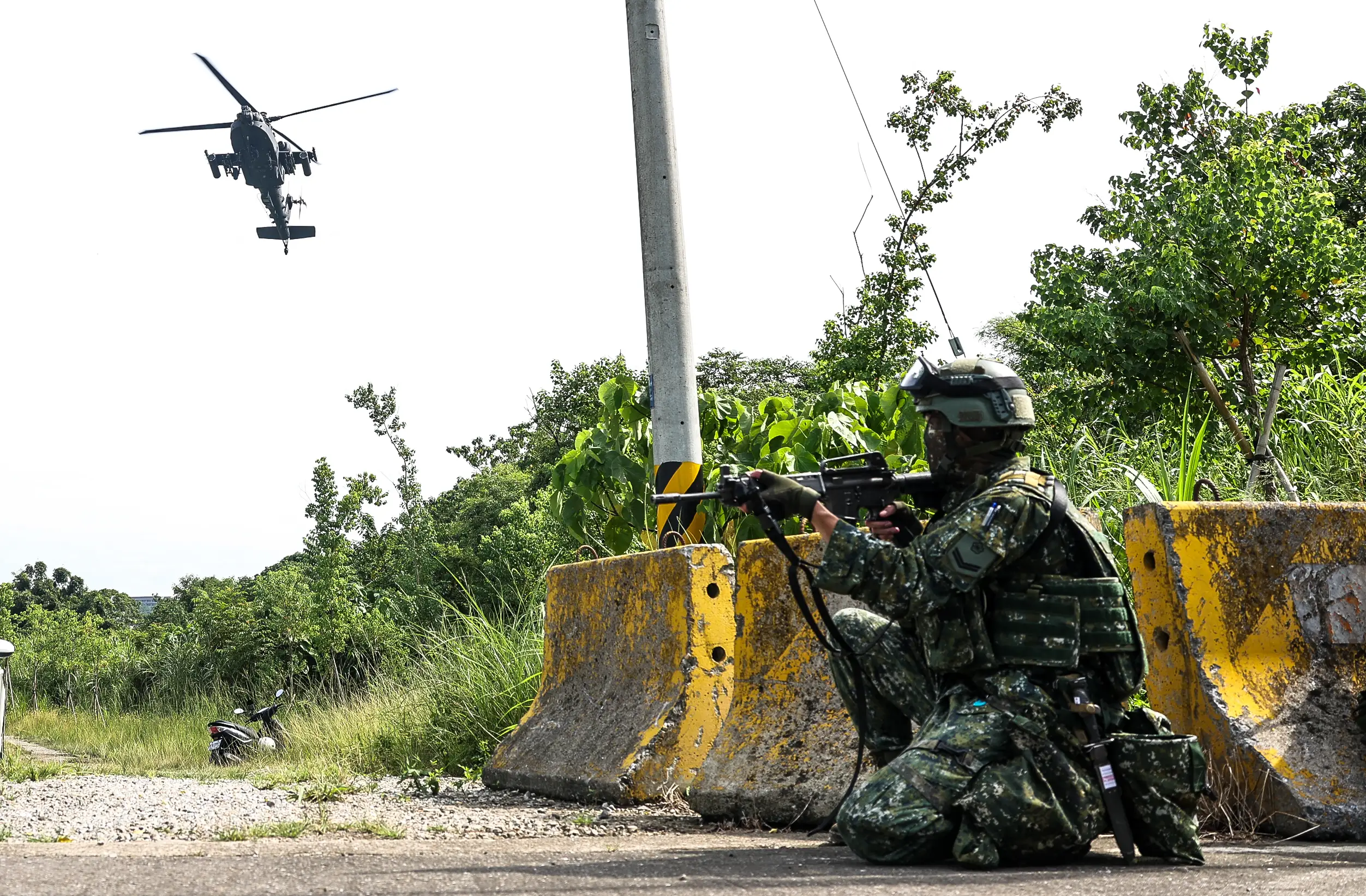 A Taiwanese soldier keeps watch on the ground as a helicotper flies in the distance.
