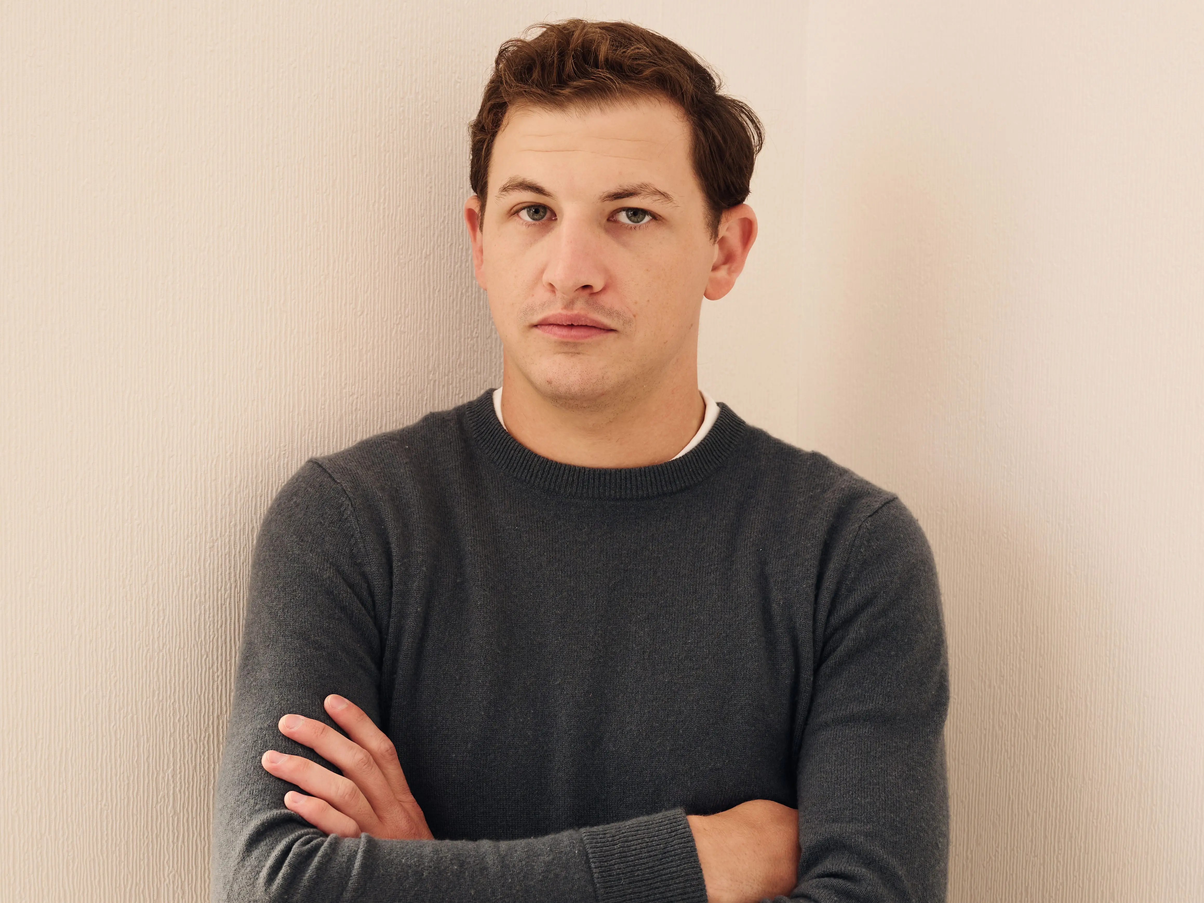 Tye Sheridan with his arms folded wearing a sweater