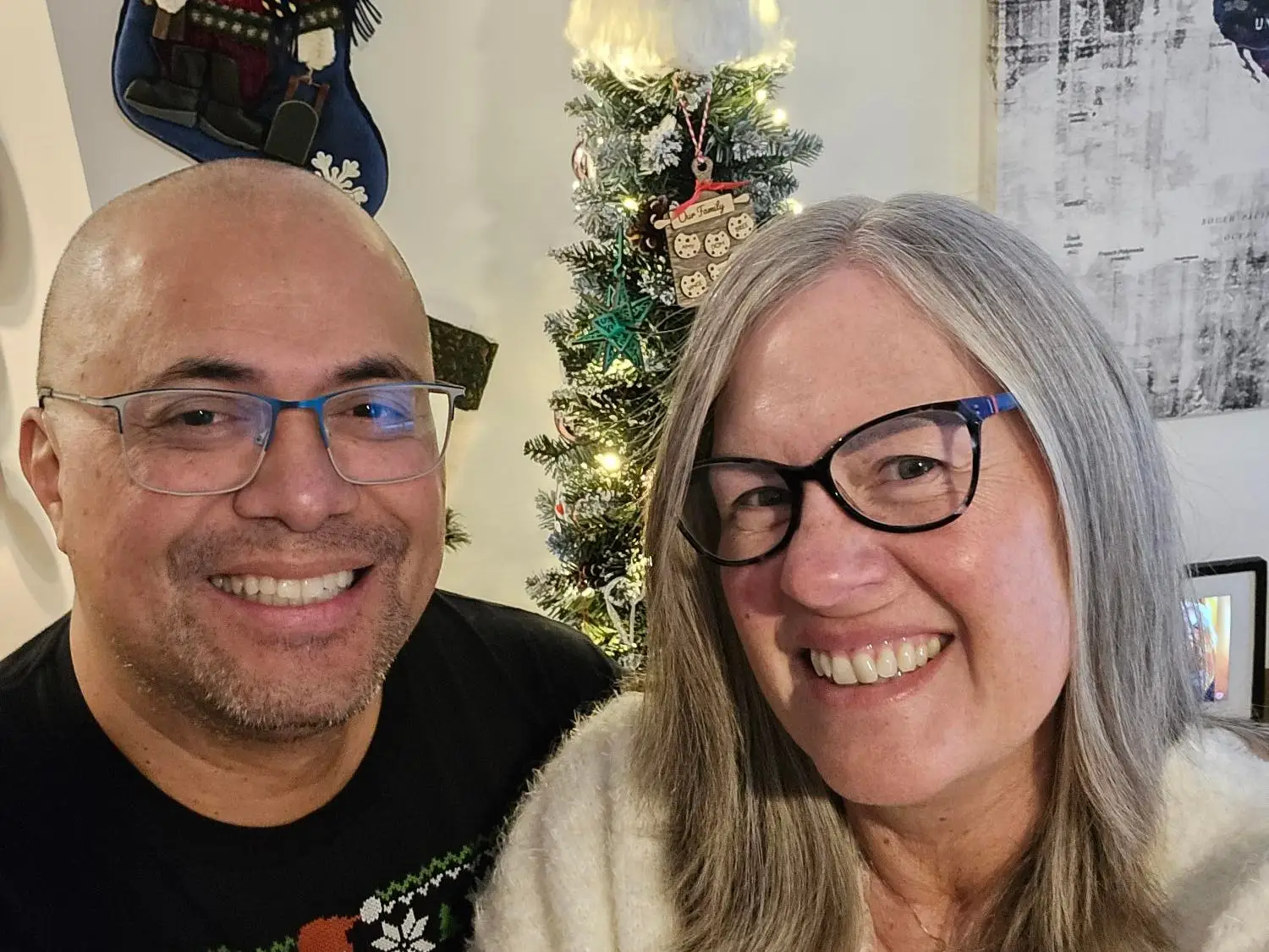 A middle-aged couple in front of a Christmas tree.