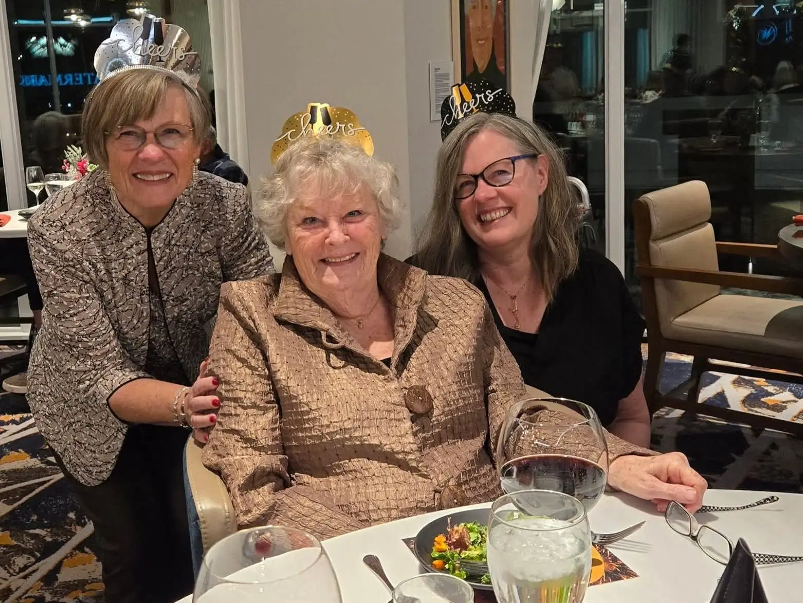 Three women wearing party hats are sitting at a table.