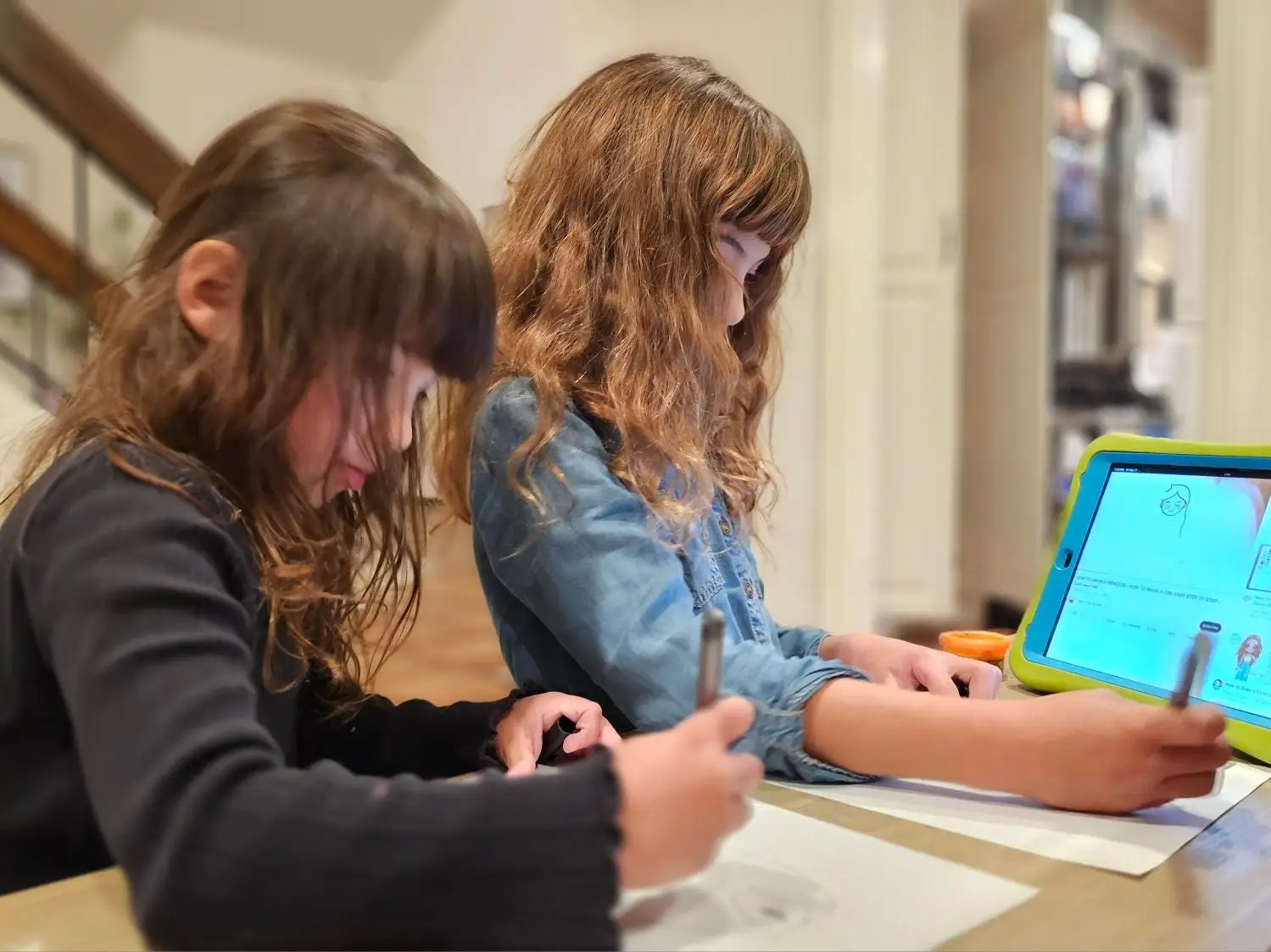 Two grade-school girls drawing from a tablet