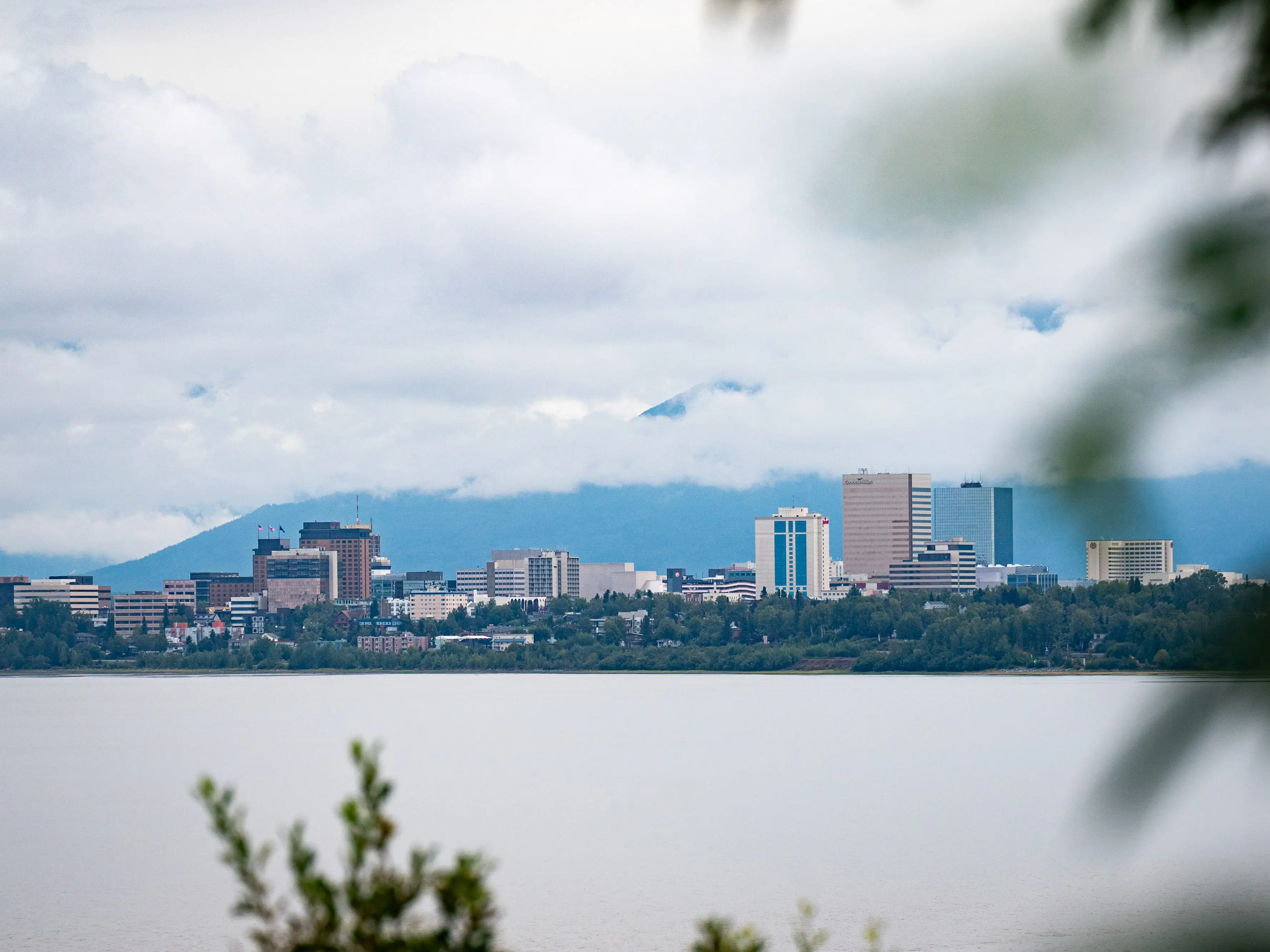 A view of a city skyline with clouds and mountains in the background.