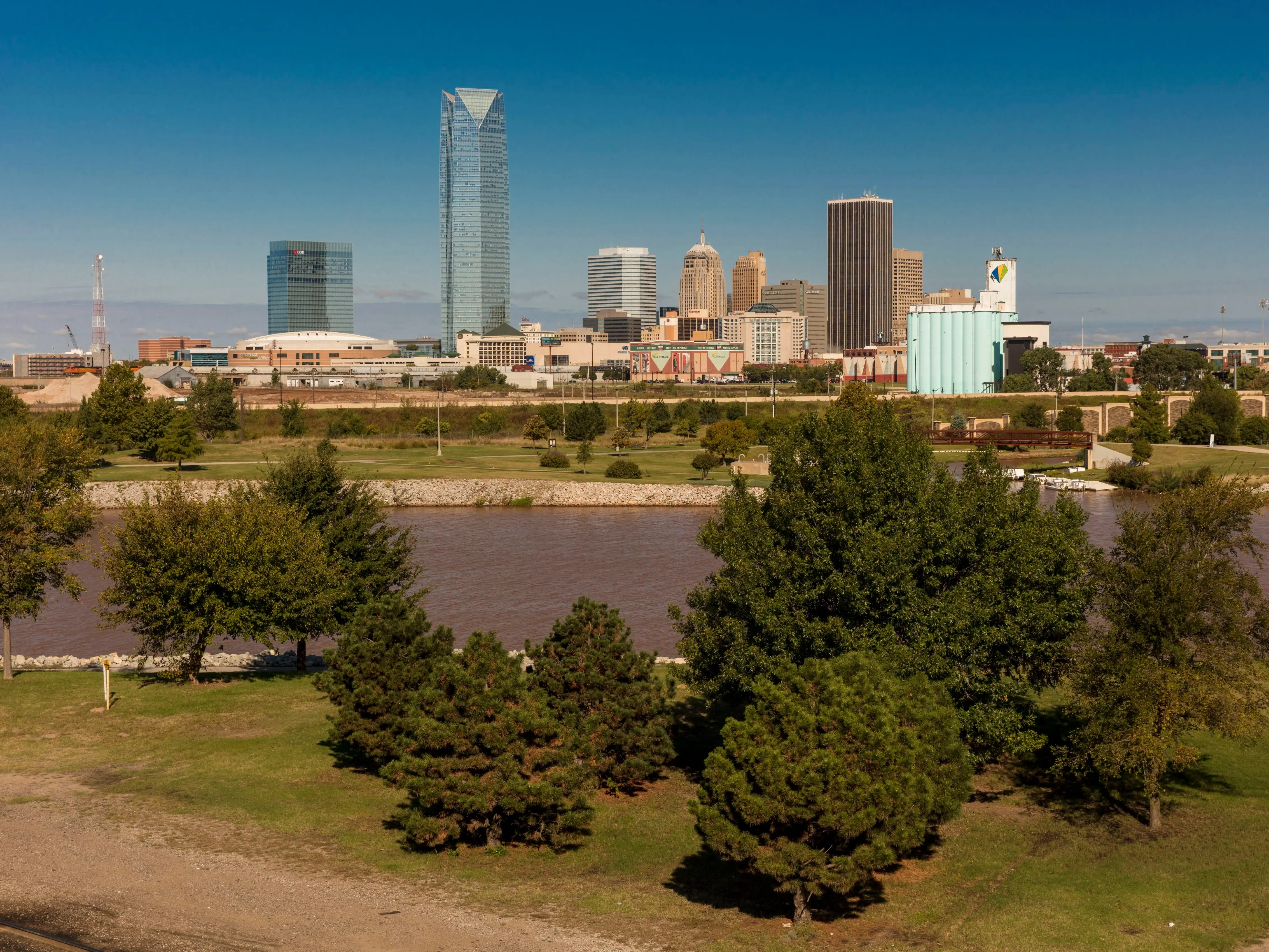 A small city skyline with trees and a river in the foreground.