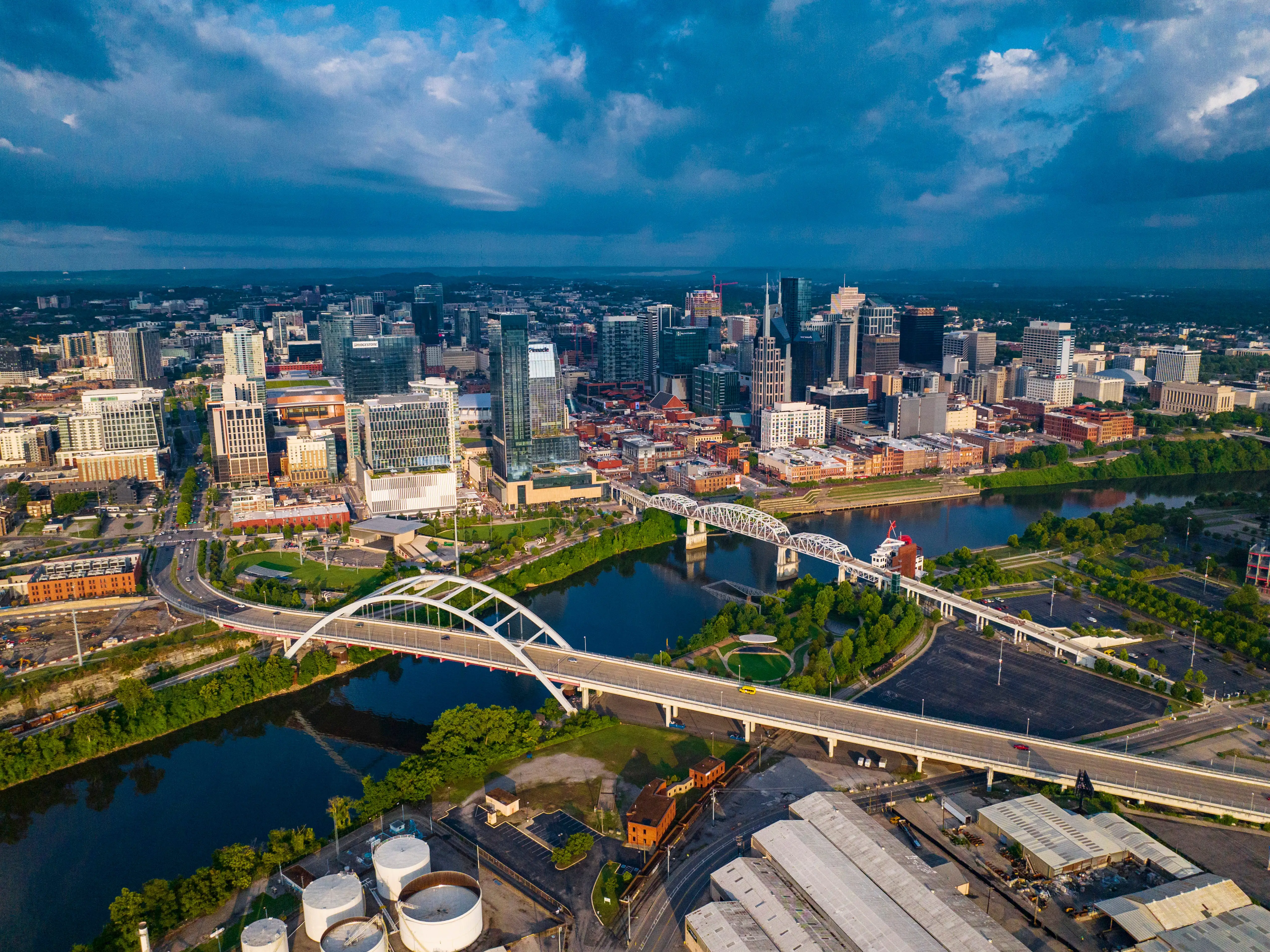 An aerial photo of a city during dusk with a river and bridges in the foreground.
