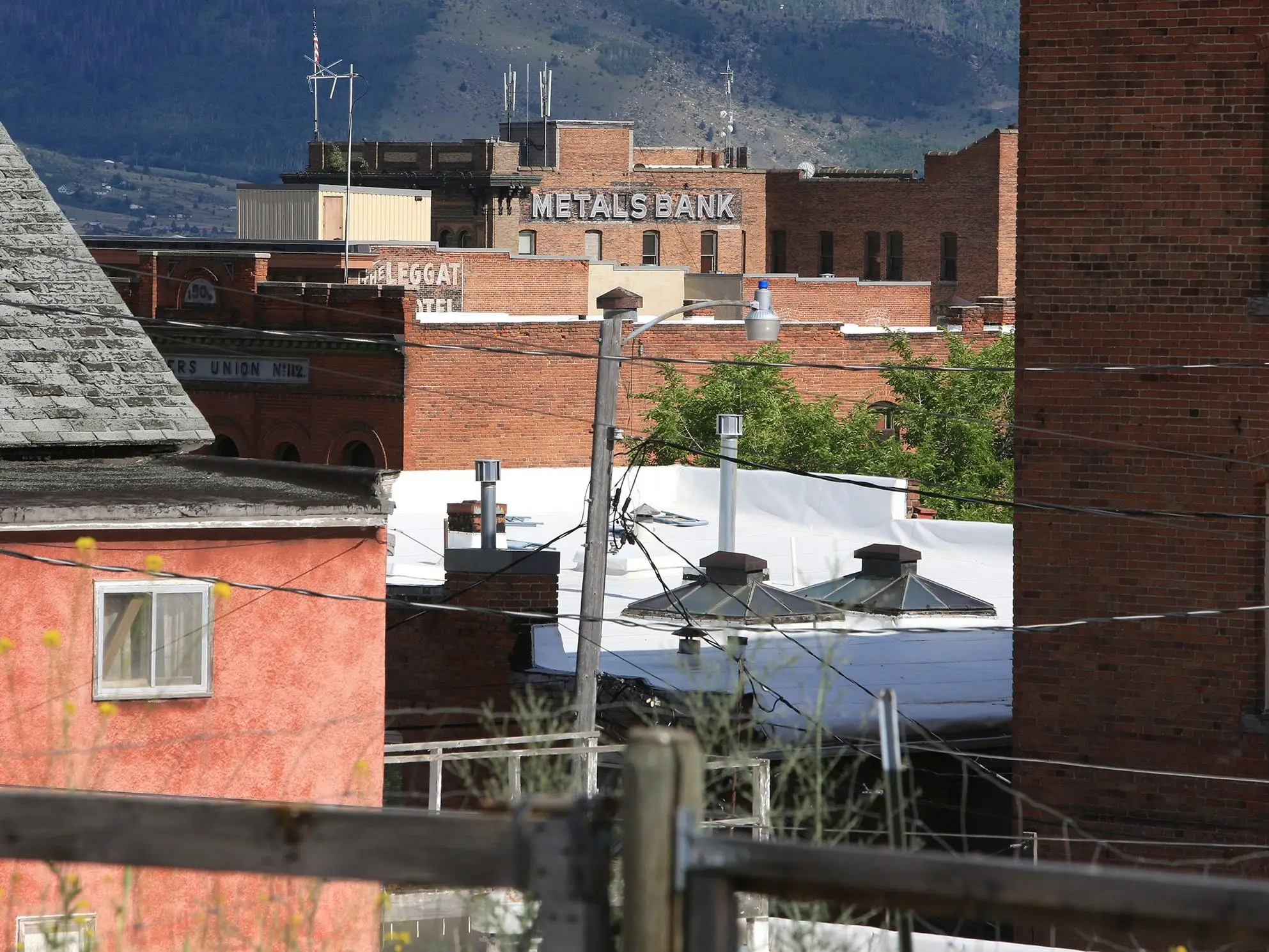 Brick buildings of a city stand together with a mountain in the background.