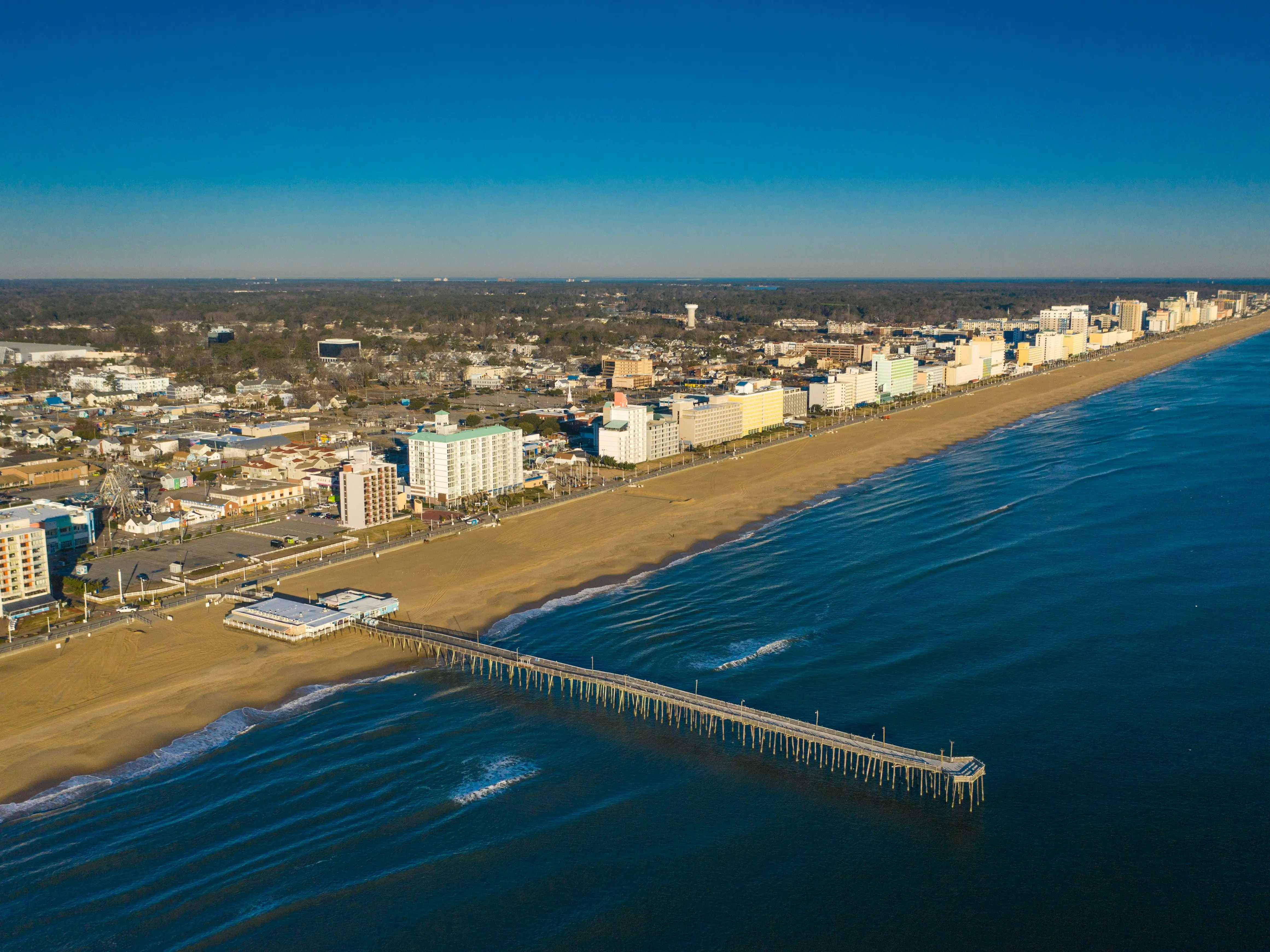 An aerial shot of a city with a pier and ocean next to it.